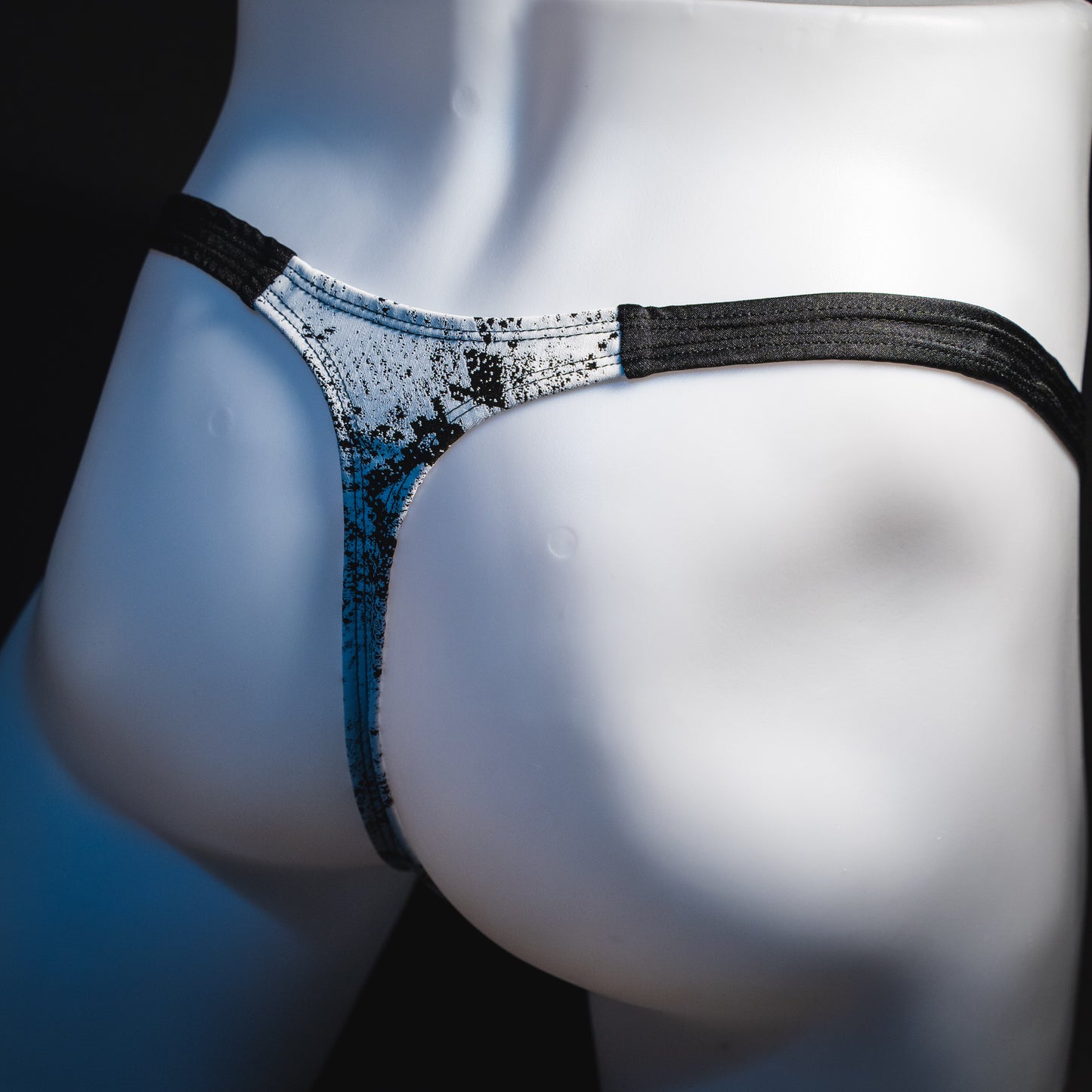 Men's black and white snakeskin thong underwear, classic cut, angled rear view.