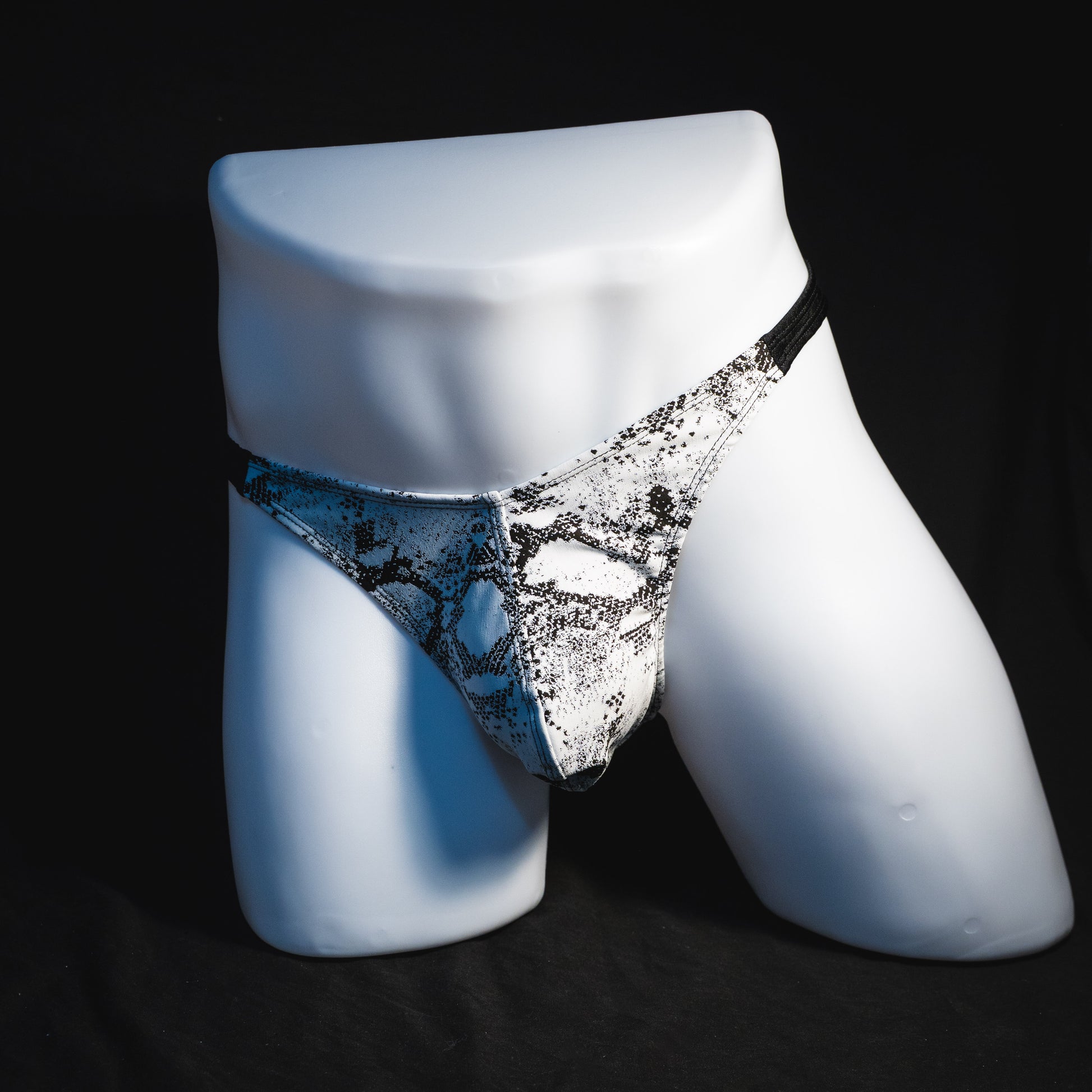 Men's black and white snakeskin thong underwear, classic cut, full angled front view.