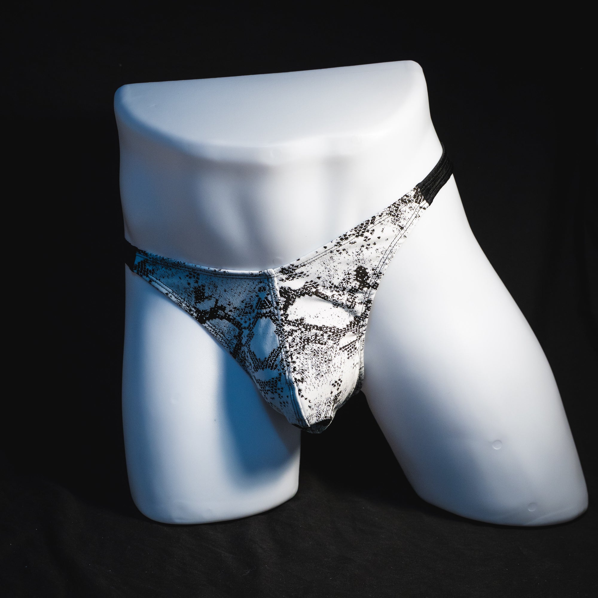 Men's black and white snakeskin thong underwear, classic cut, full angled front view.