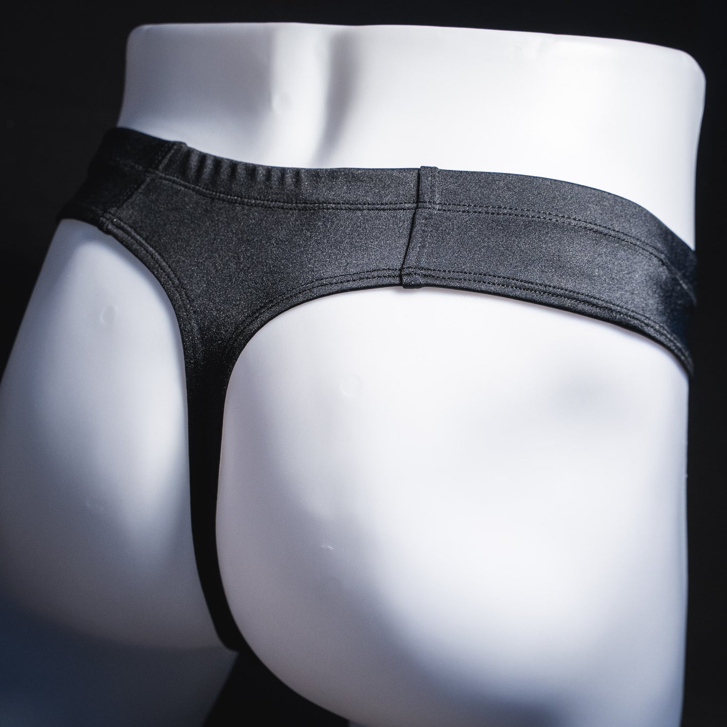 Men's black brief cut thong underwear, angled rear view.