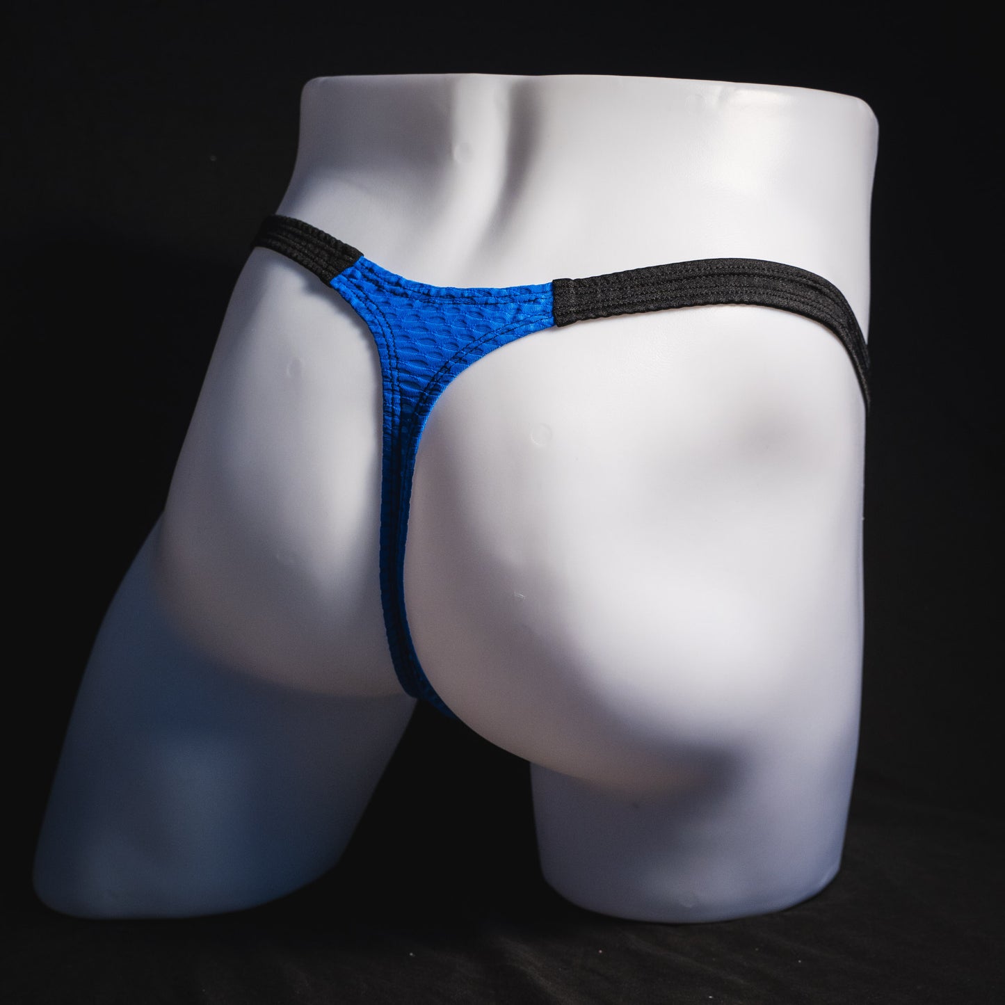 Men's blue and black athletic mesh thong underwear, classic cut, full angled rear view.