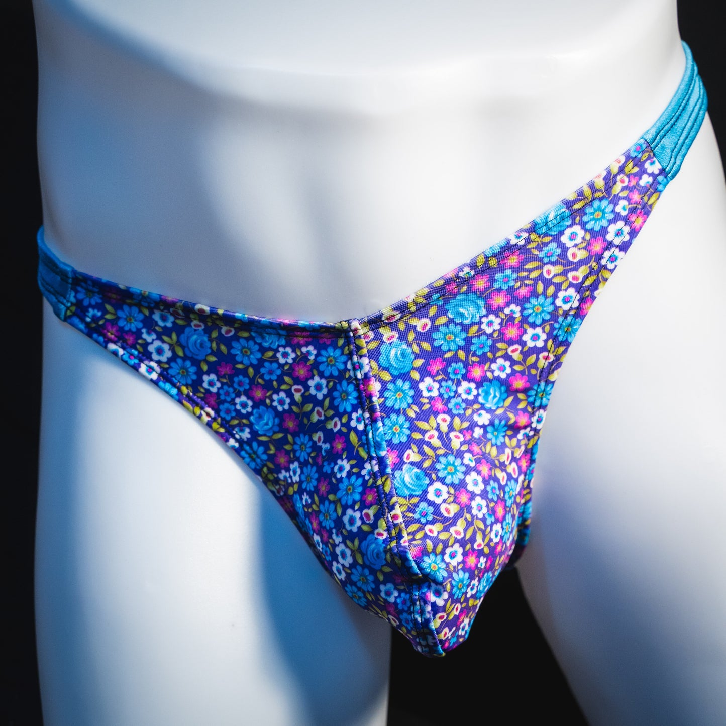 Men's blue and purple flower patch thong underwear, classic cut, front view.
