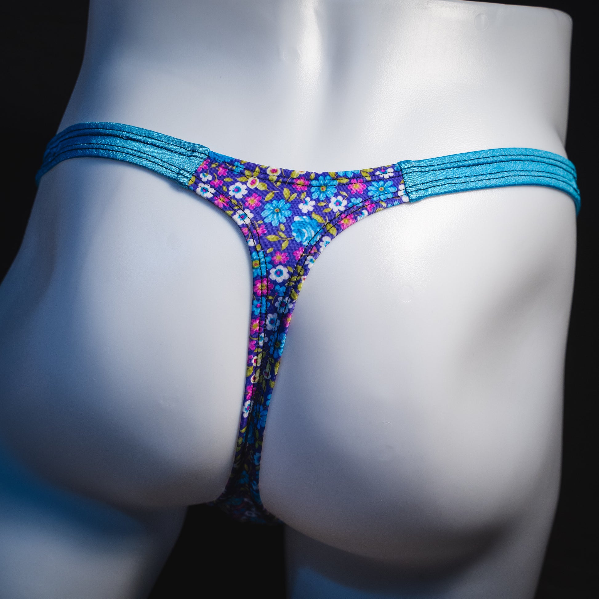 Men's blue and purple flower patch thong underwear, classic cut, rear view.