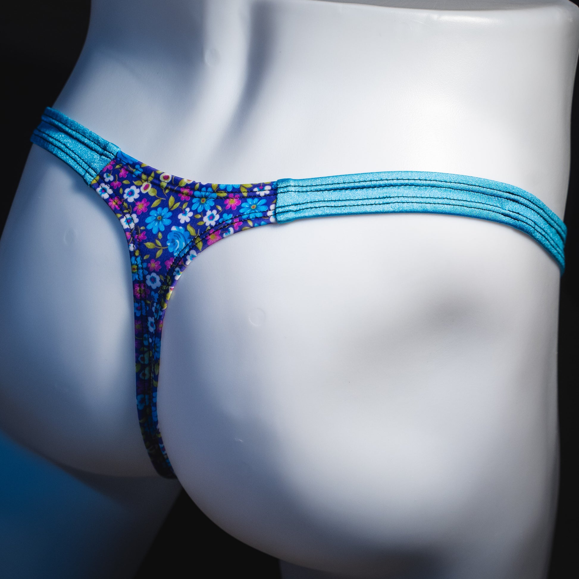 Men's blue and purple flower patch thong underwear, classic cut, angled rear view,