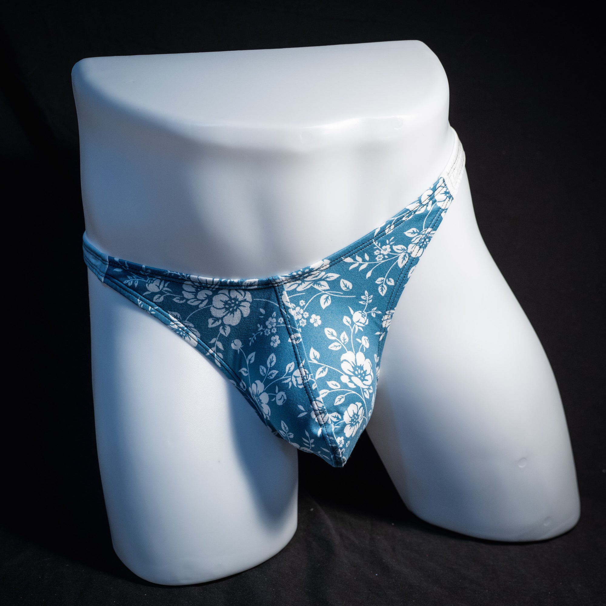 Men's blue and white floral thong underwear, classic cut, front view.