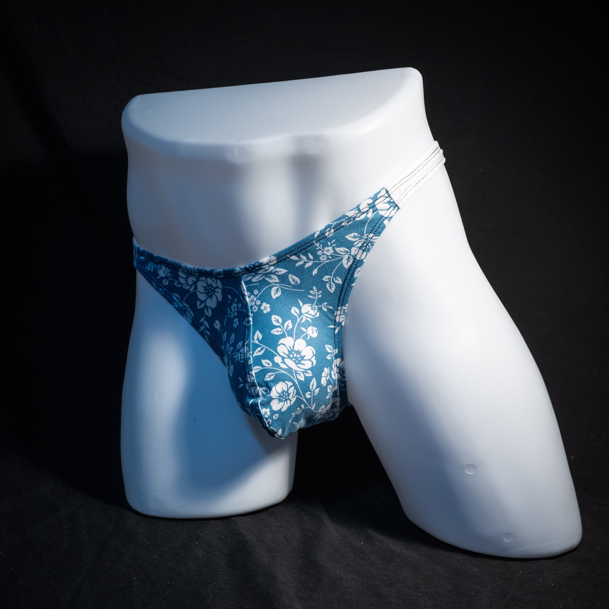 Men's blue and white floral thong underwear, classic cut, front view.
