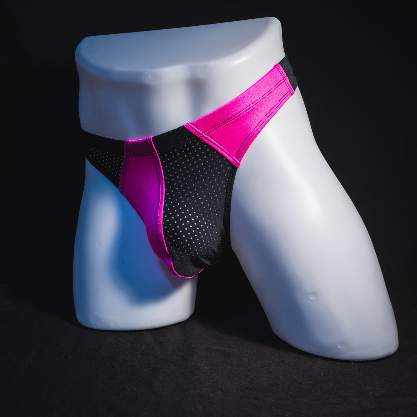 Men's bright pink and black mesh thong underwear, full angled front view.