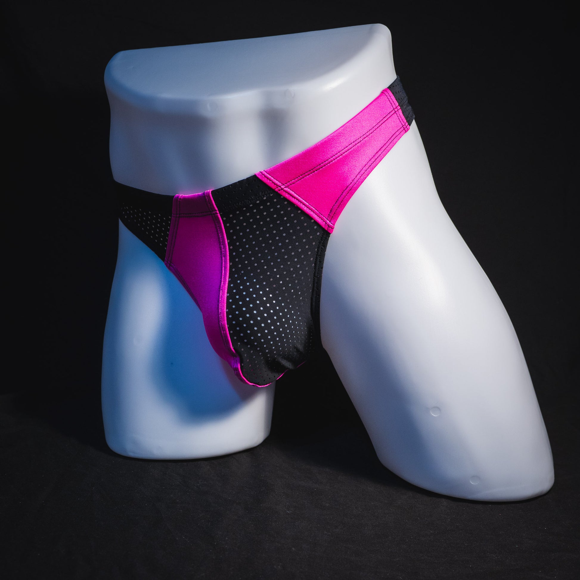 Men's bright pink and black mesh thong underwear, full angled front view.