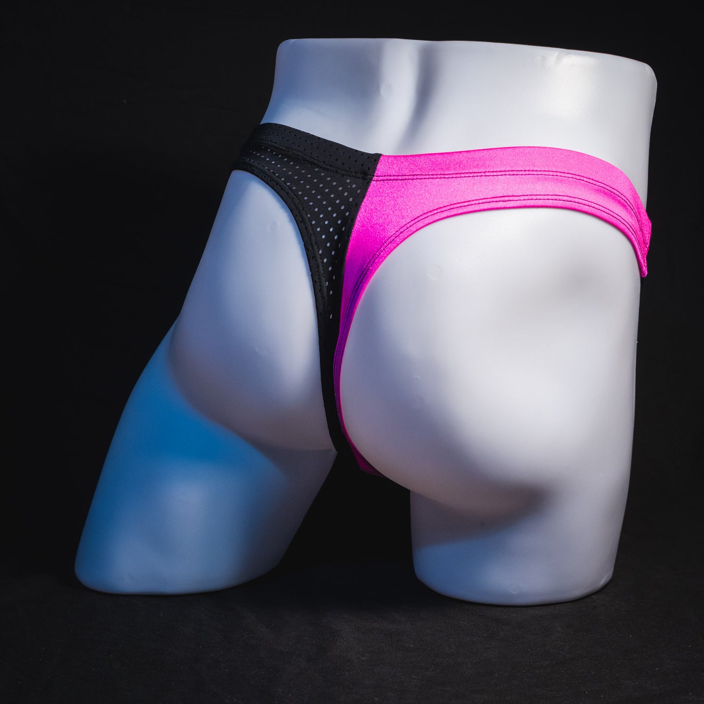 Men's bright pink and black mesh thong underwear, full angled rear view.