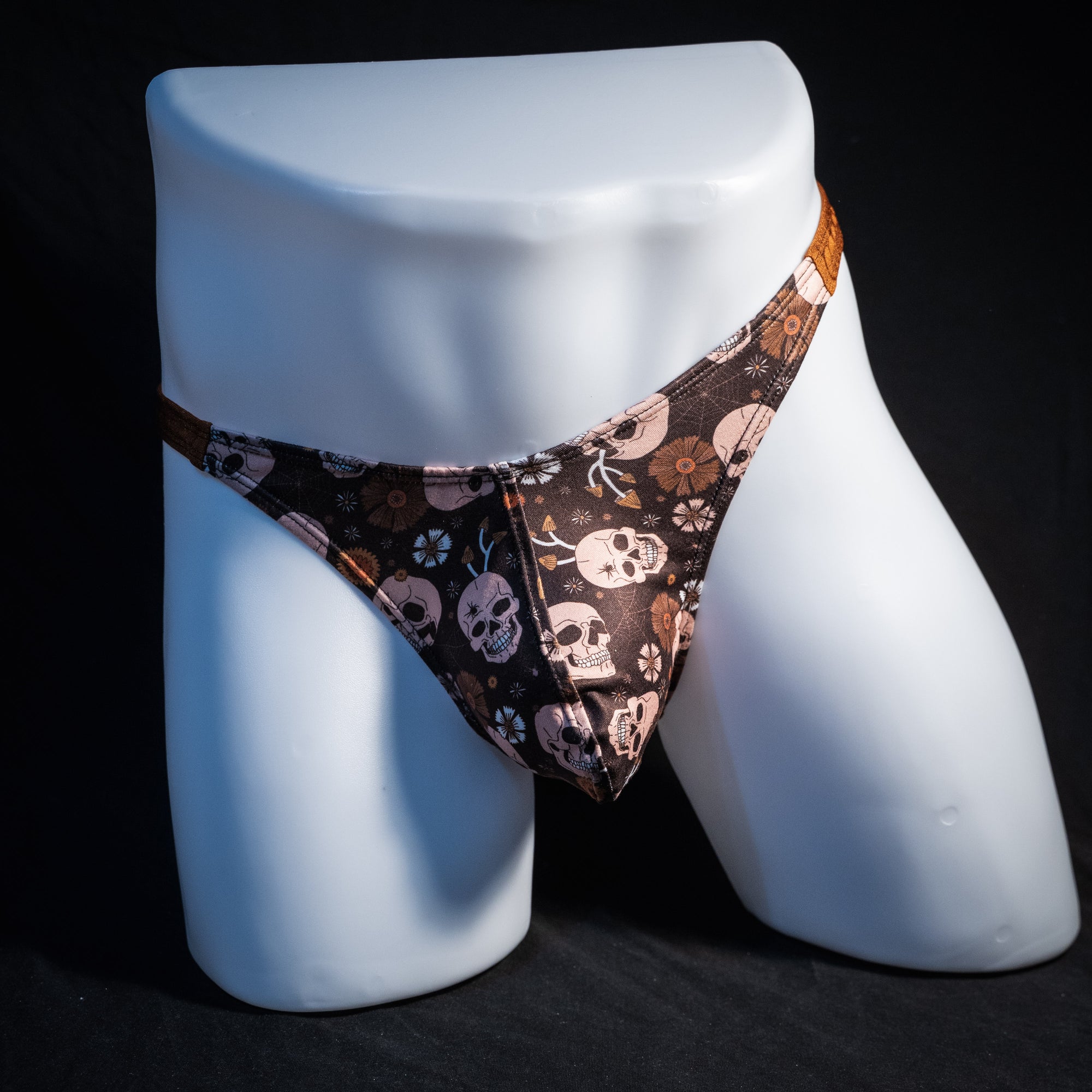 Men's brown skull patterned thong underwear, classic cut, front view.