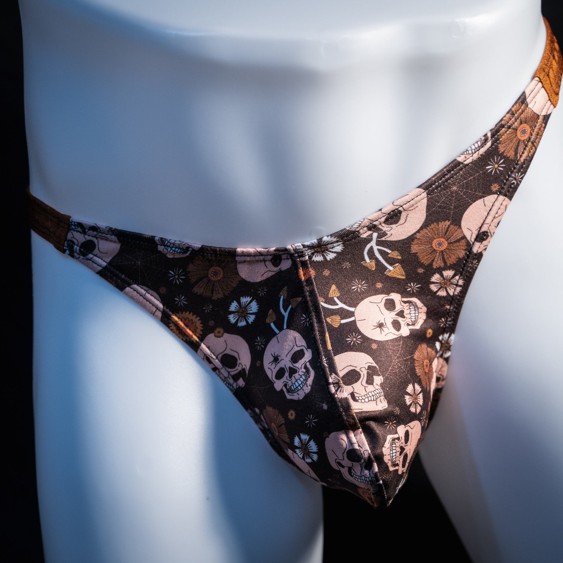 Men's brown skull patterned thong underwear, classic cut, front view.