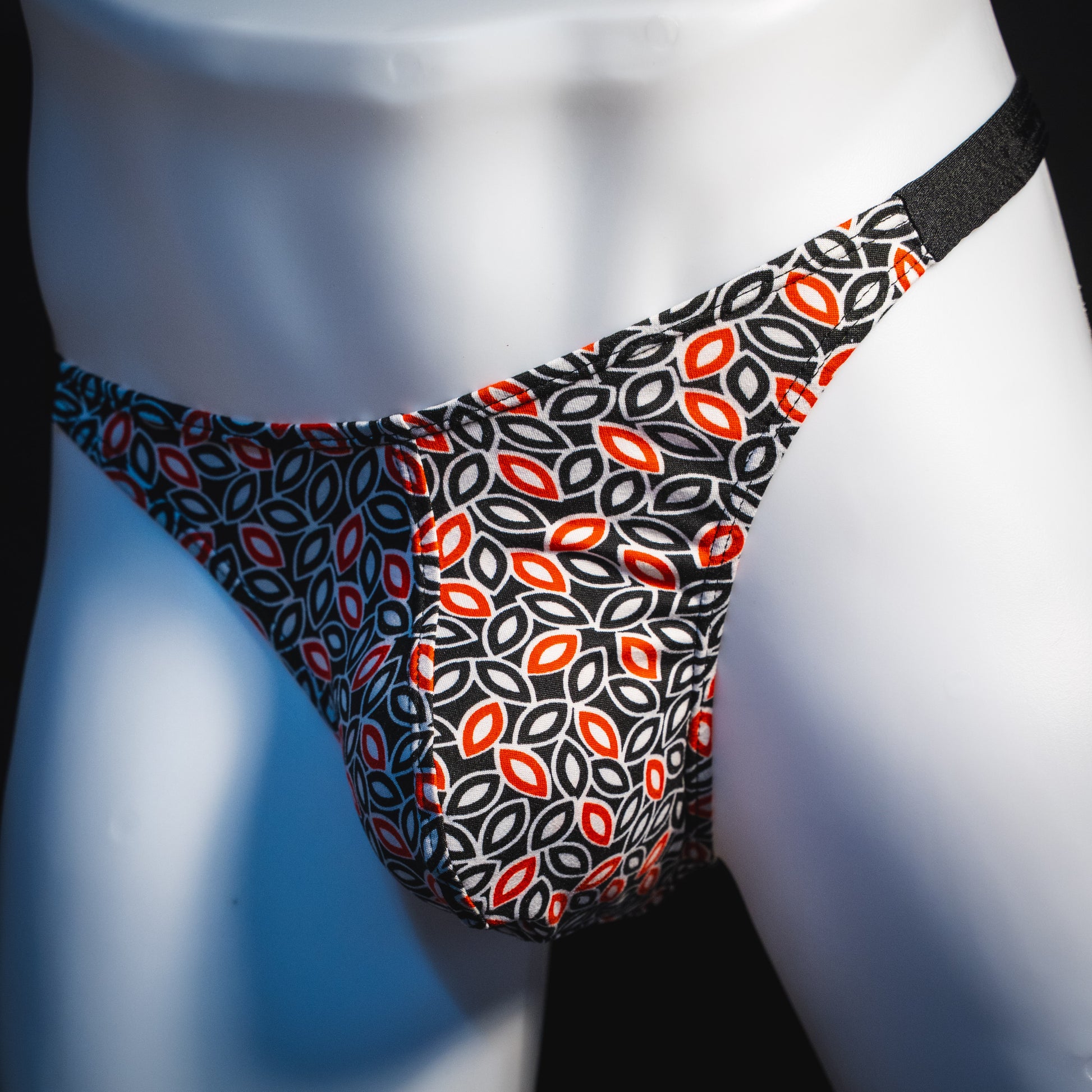 Men's black white and red petal thong underwear, classic cut, angled front view.