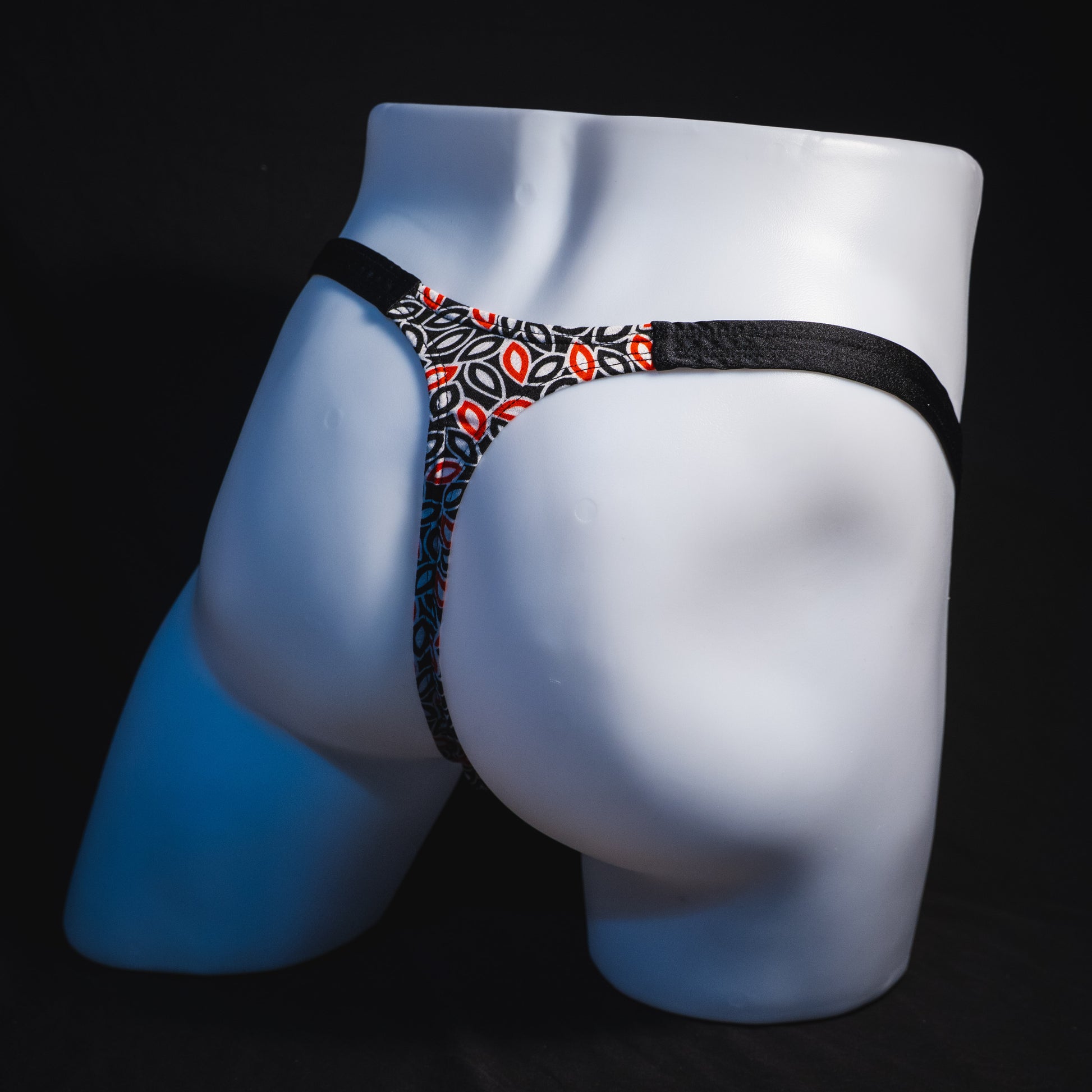 Men's black white and red petal thong underwear, classic cut, full angled rear view.