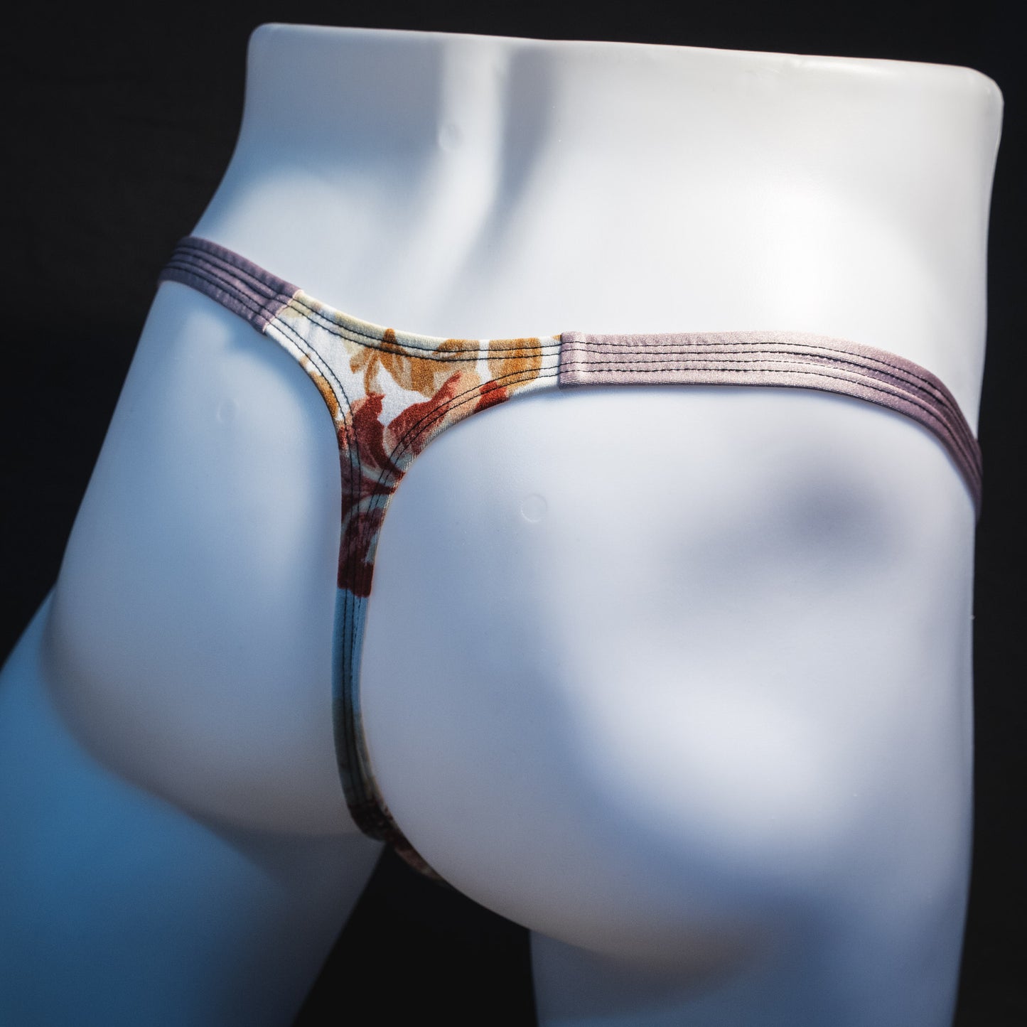 Men's ivory floral thong underwear, classic cut, rear angled view.