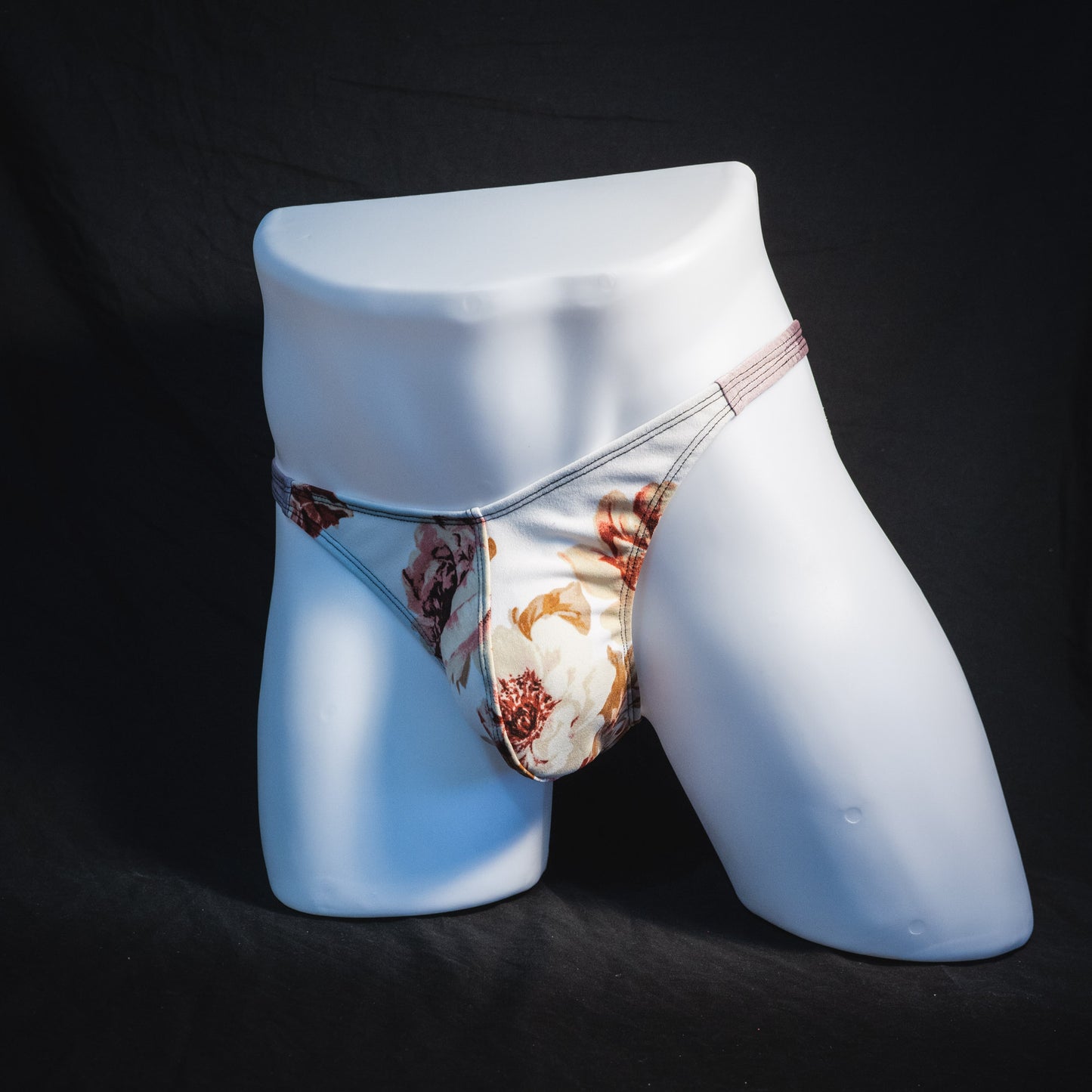 Men's ivory floral thong underwear, classic cut, full front angled view.