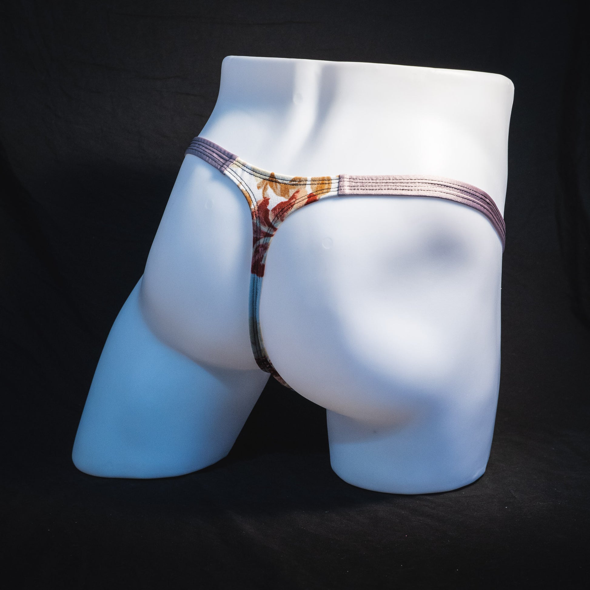Men's ivory floral thong underwear, classic cut, full rear angled view.