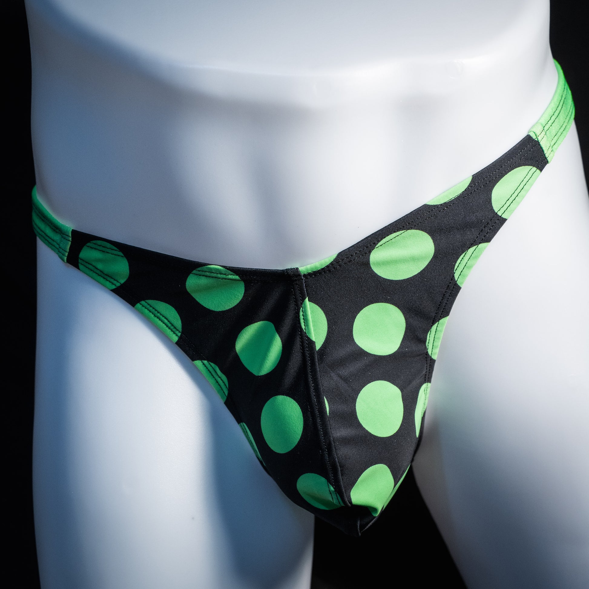 Men's green and black polka dot thong underwear, classic cut, front view.