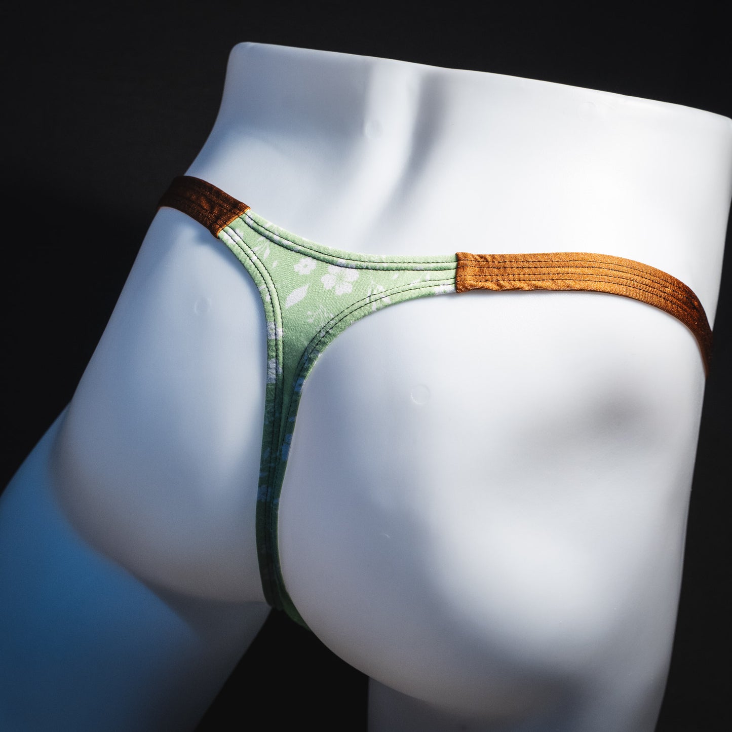 Men's green floral thong underwear, tear drop cut, angled rear view.