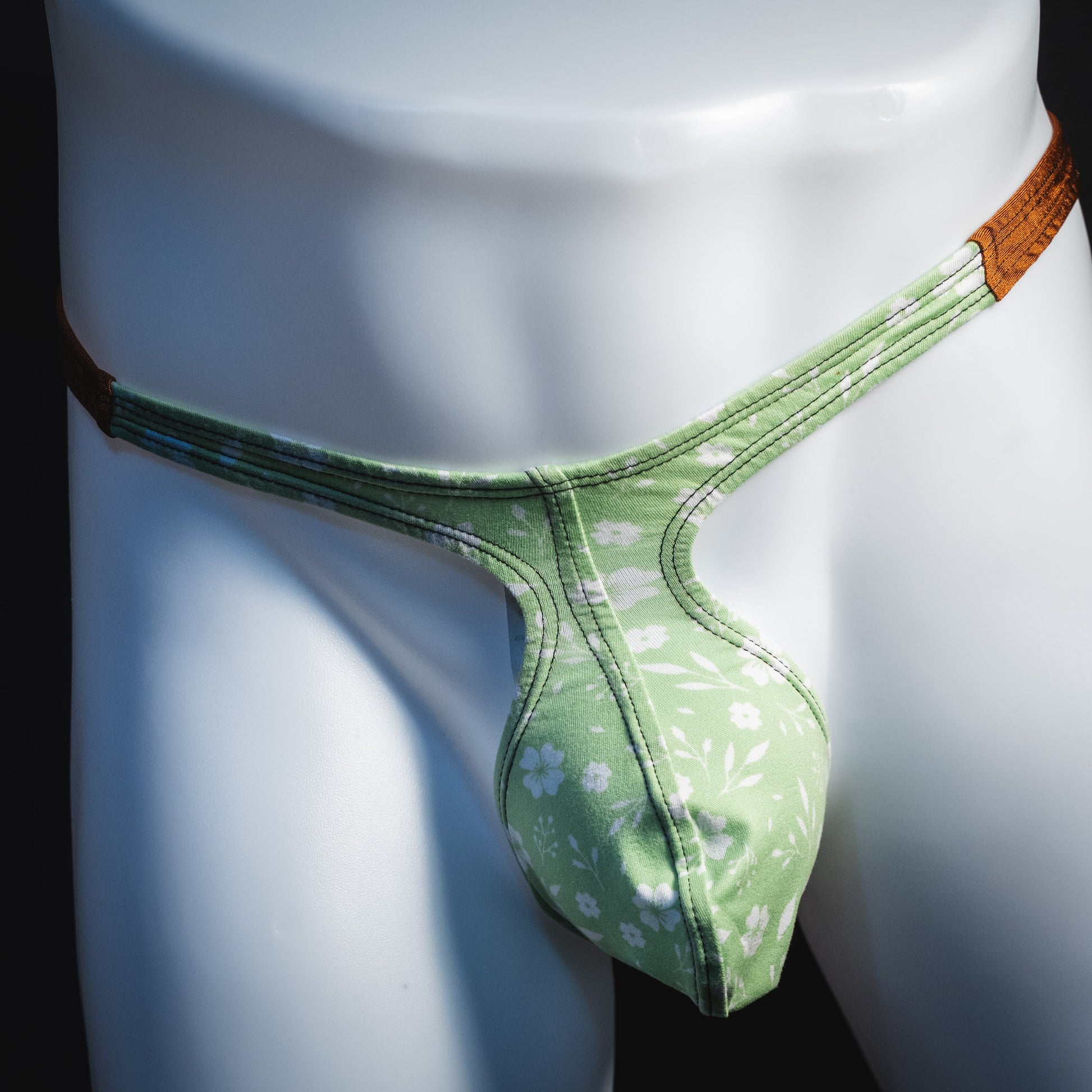Men's green floral thong underwear, tear drop cut, front view.