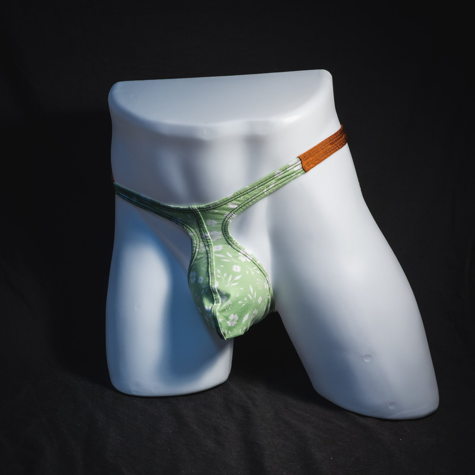 Men's green floral thong underwear, tear drop cut, full angled front view.