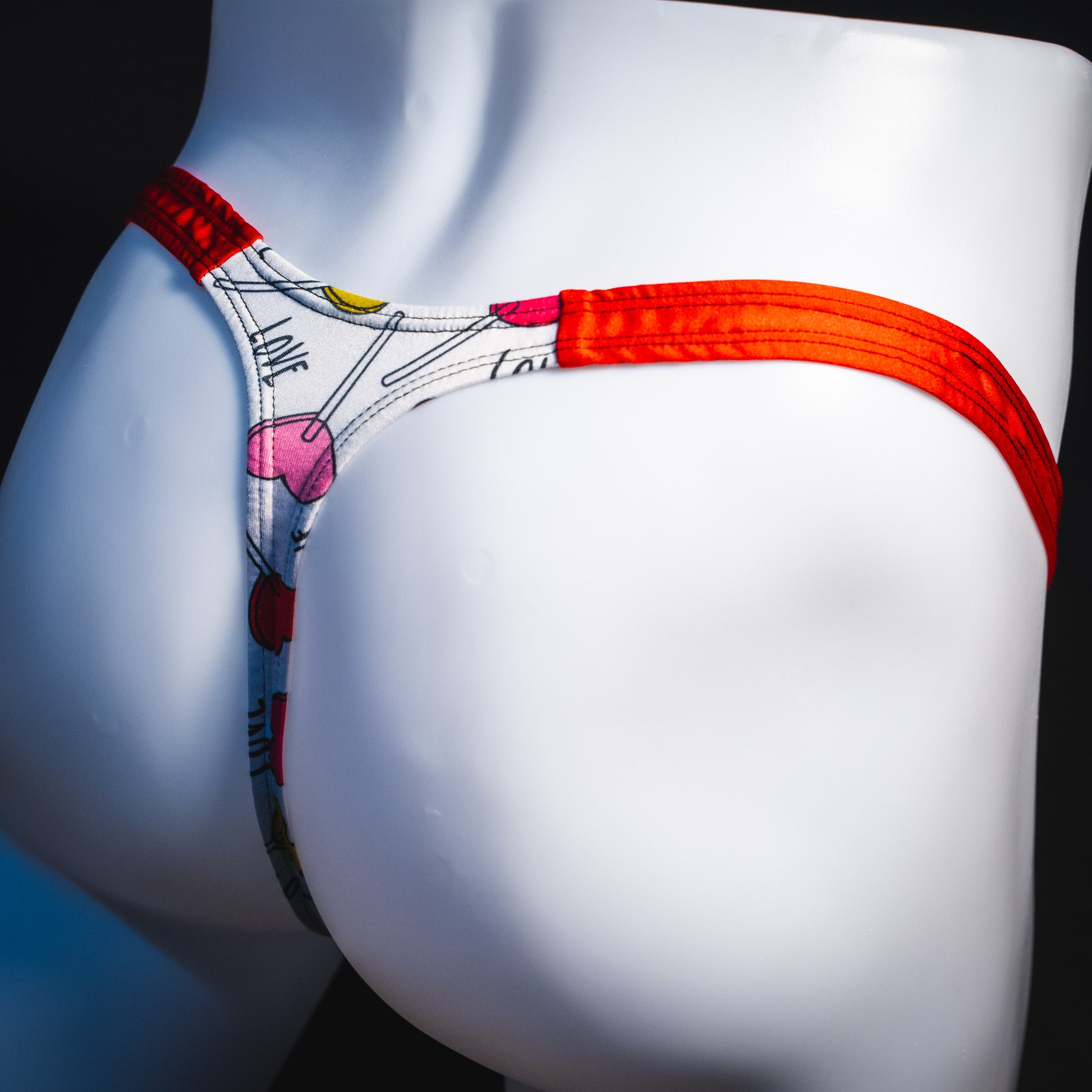 Men's heart shaped lollipops thong underwear, classic cut, angled rear view.