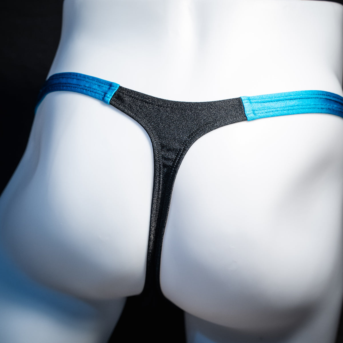 Men's black mesh and teal thong underwear, classic cut, rear view.