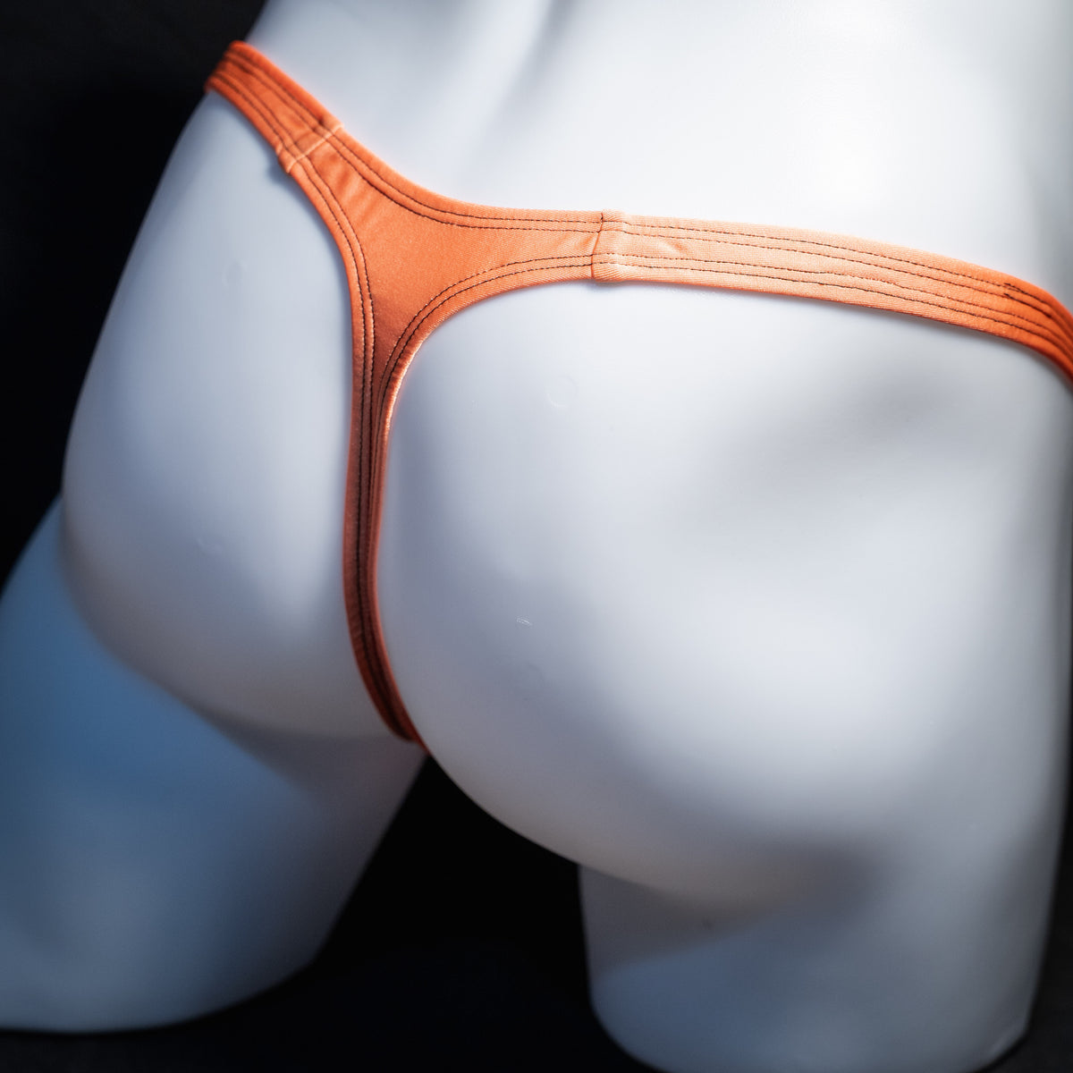 Men's neon orange thong underwear, classic cut, rear view.