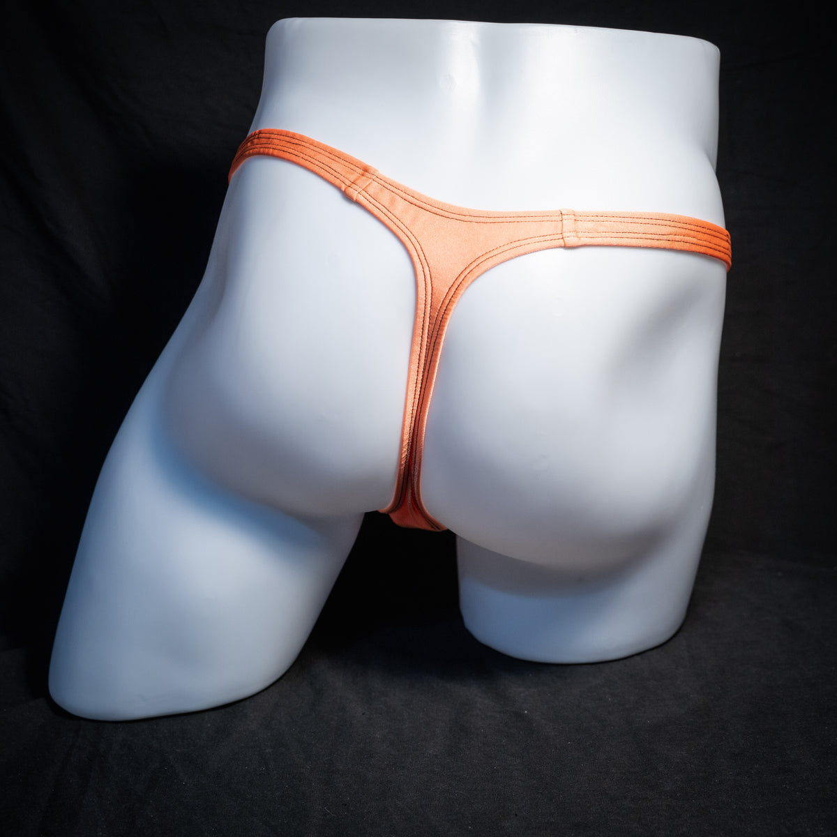 Men's neon orange thong underwear, classic cut, rear view.