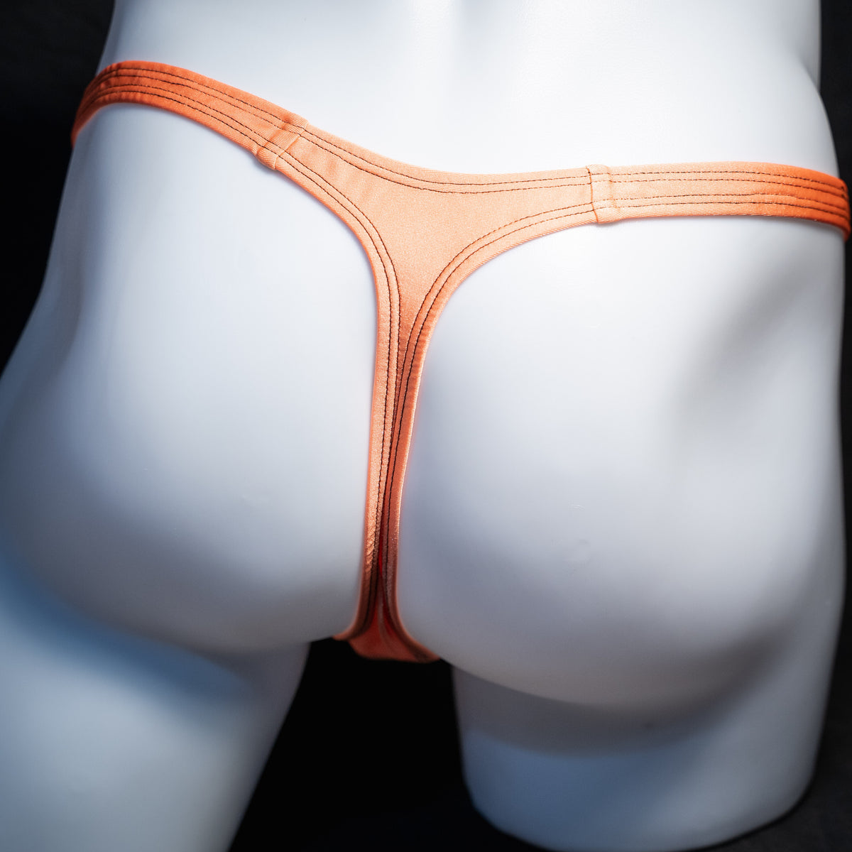 Men's neon orange thong underwear, classic cut, rear view.
