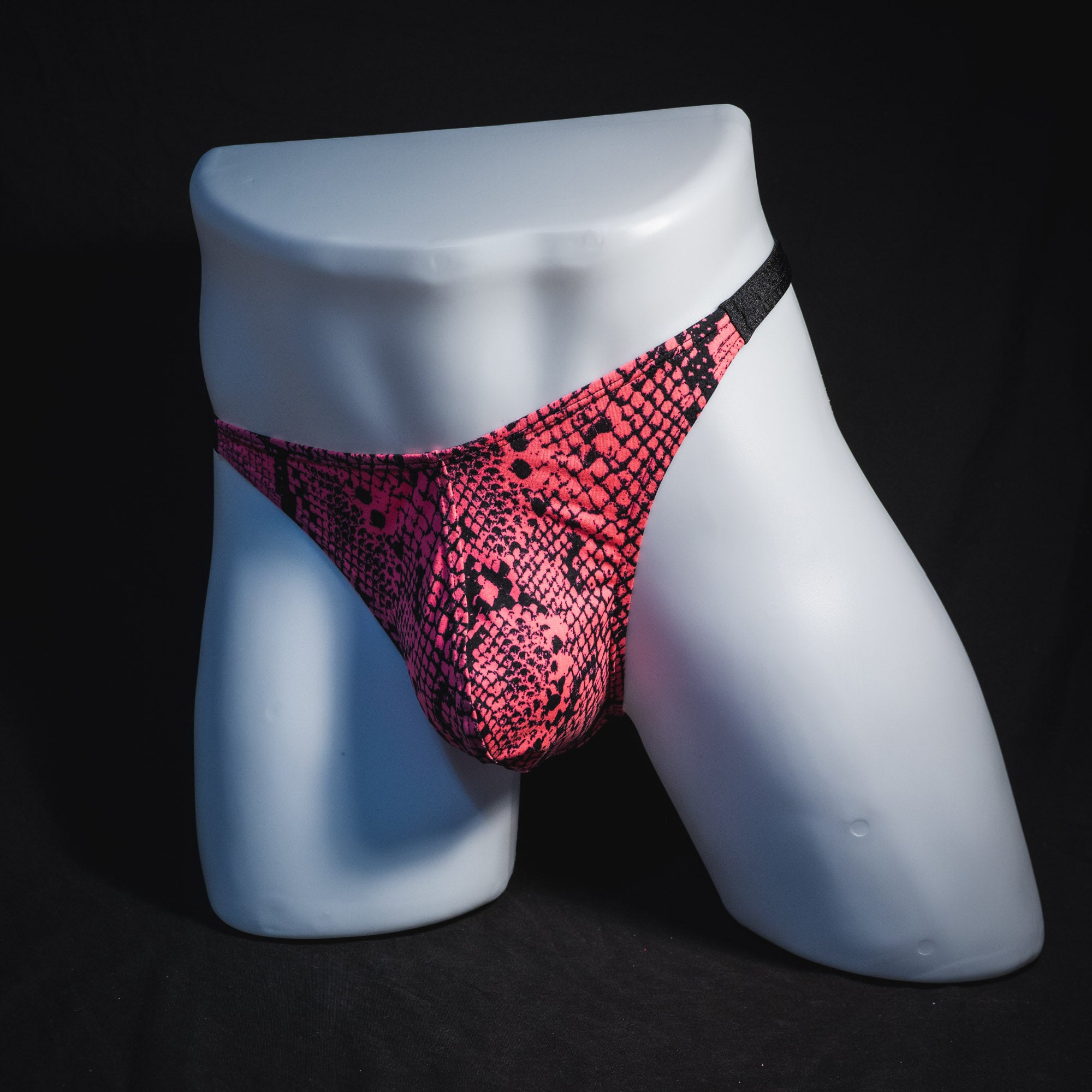 Men's neon pink snakeskin thong underwear, classic cut, full angled front view.