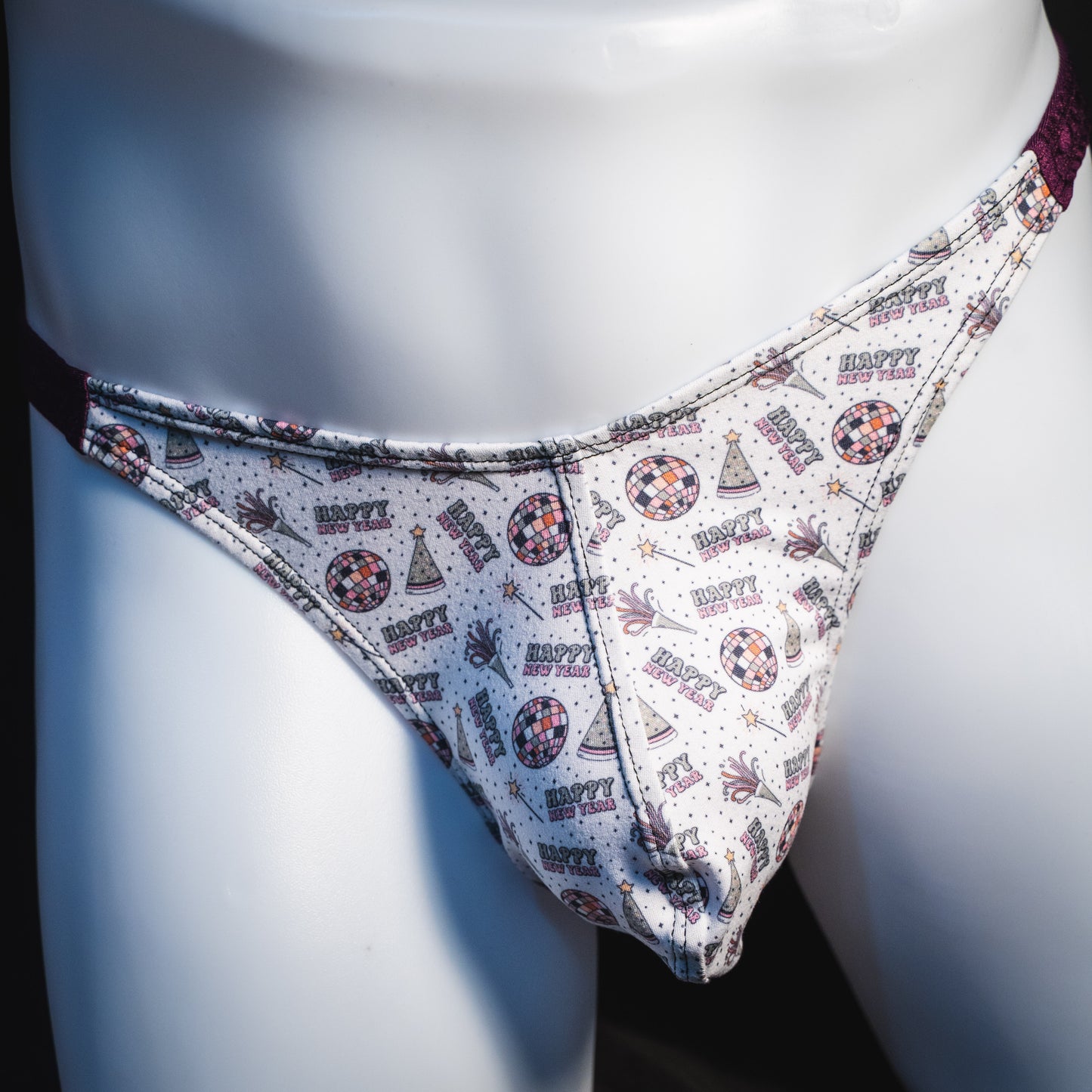 Men's new years thong underwear with shiny purple straps, classic cut, front view.