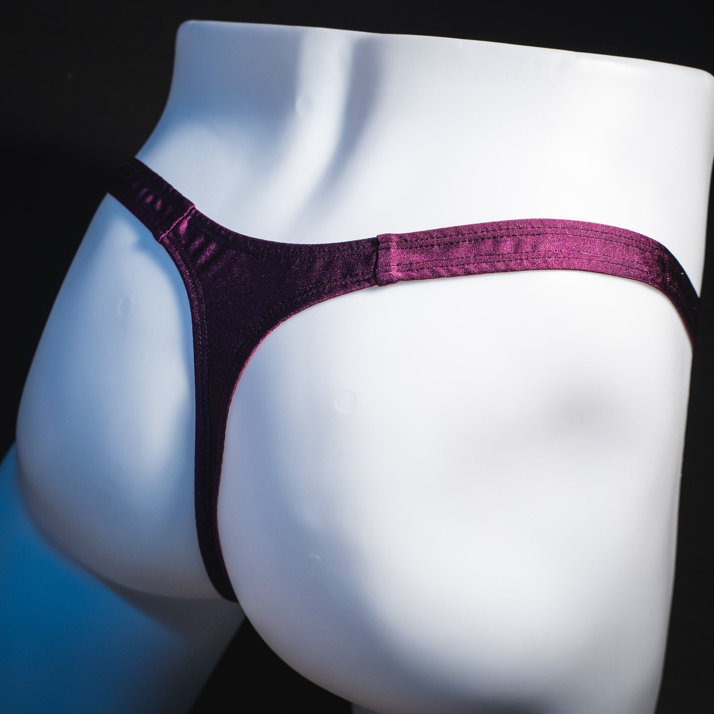 Men's new years thong underwear with shiny purple straps, classic cut, angled rear view.