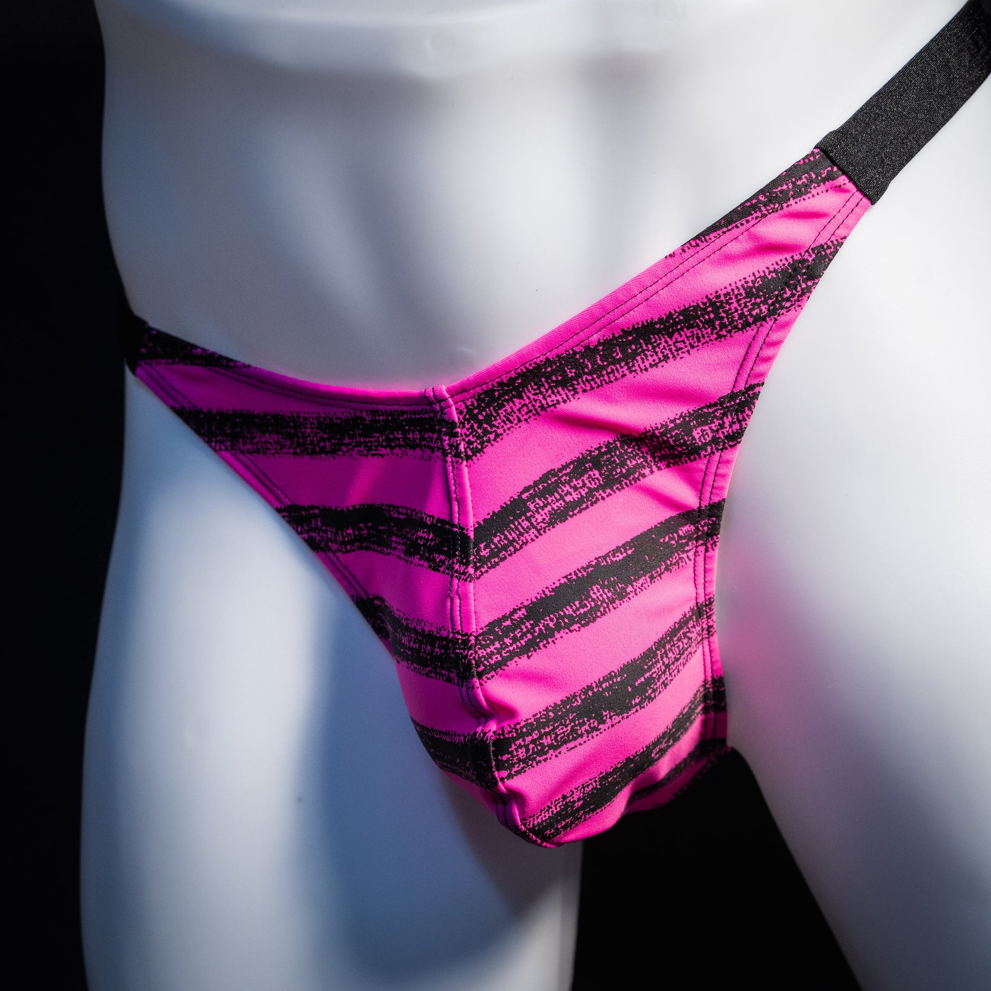Men's pink and black striped thong underwear, classic cut, front view.