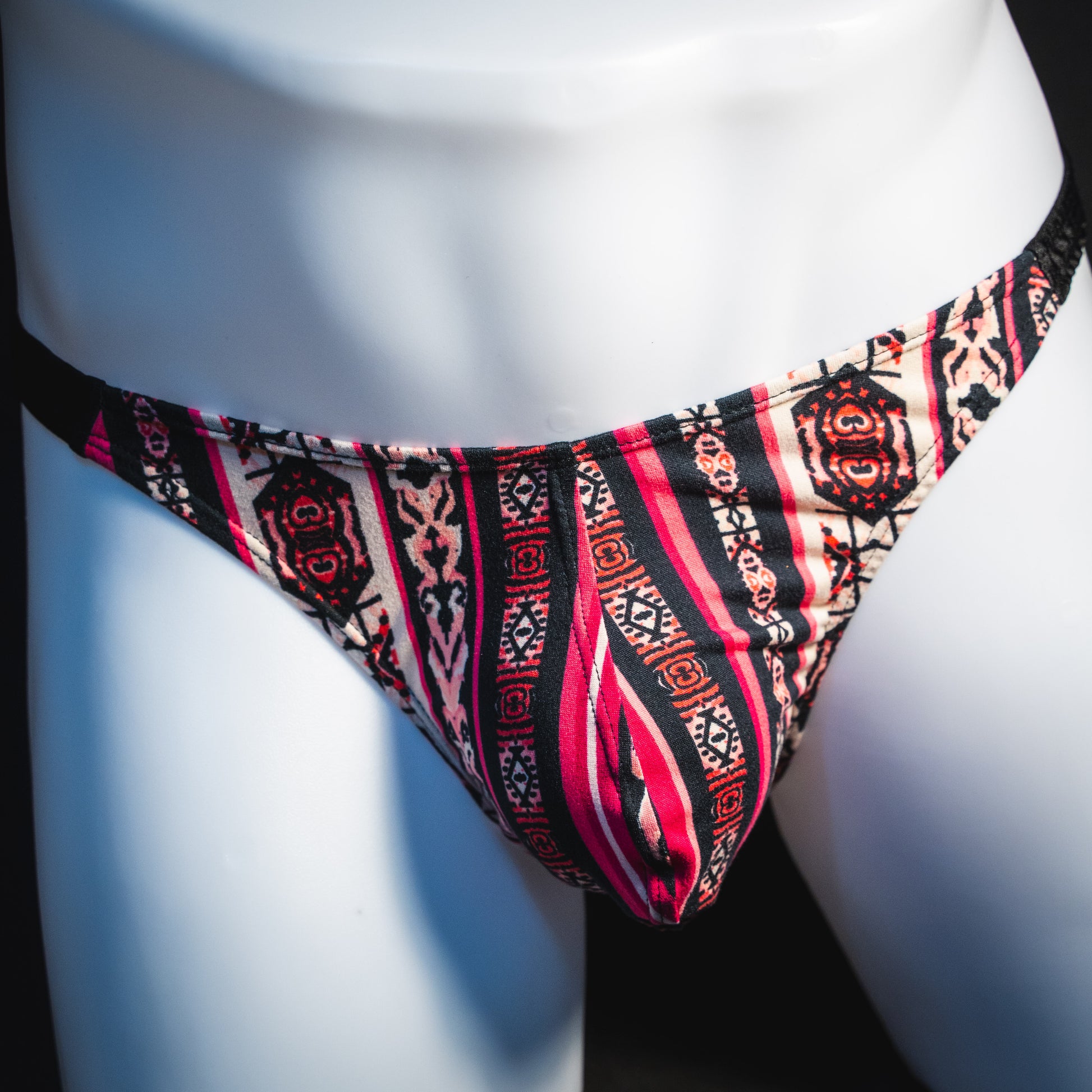 Men's pink bohemian striped thong underwear, classic cut, front view.