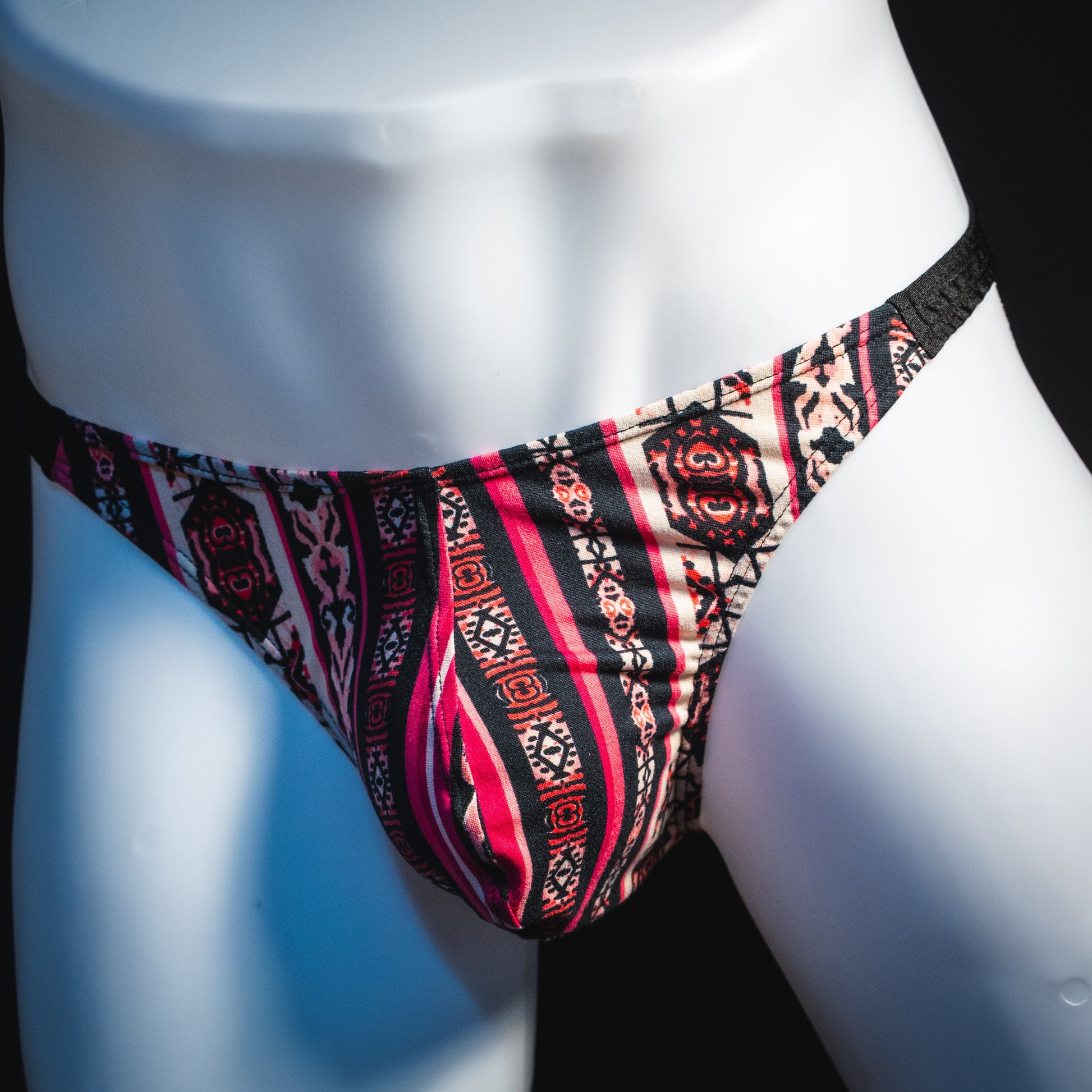 Men's pink bohemian striped thong underwear, classic cut, front angled view.