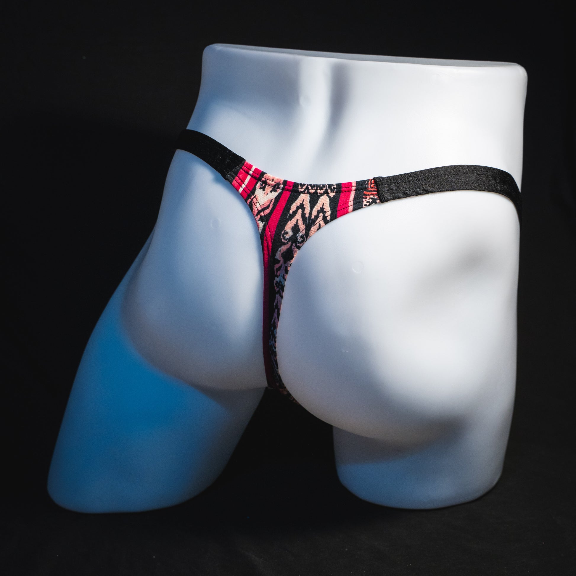 Men's pink bohemian striped thong underwear, classic cut, full angled rear view.