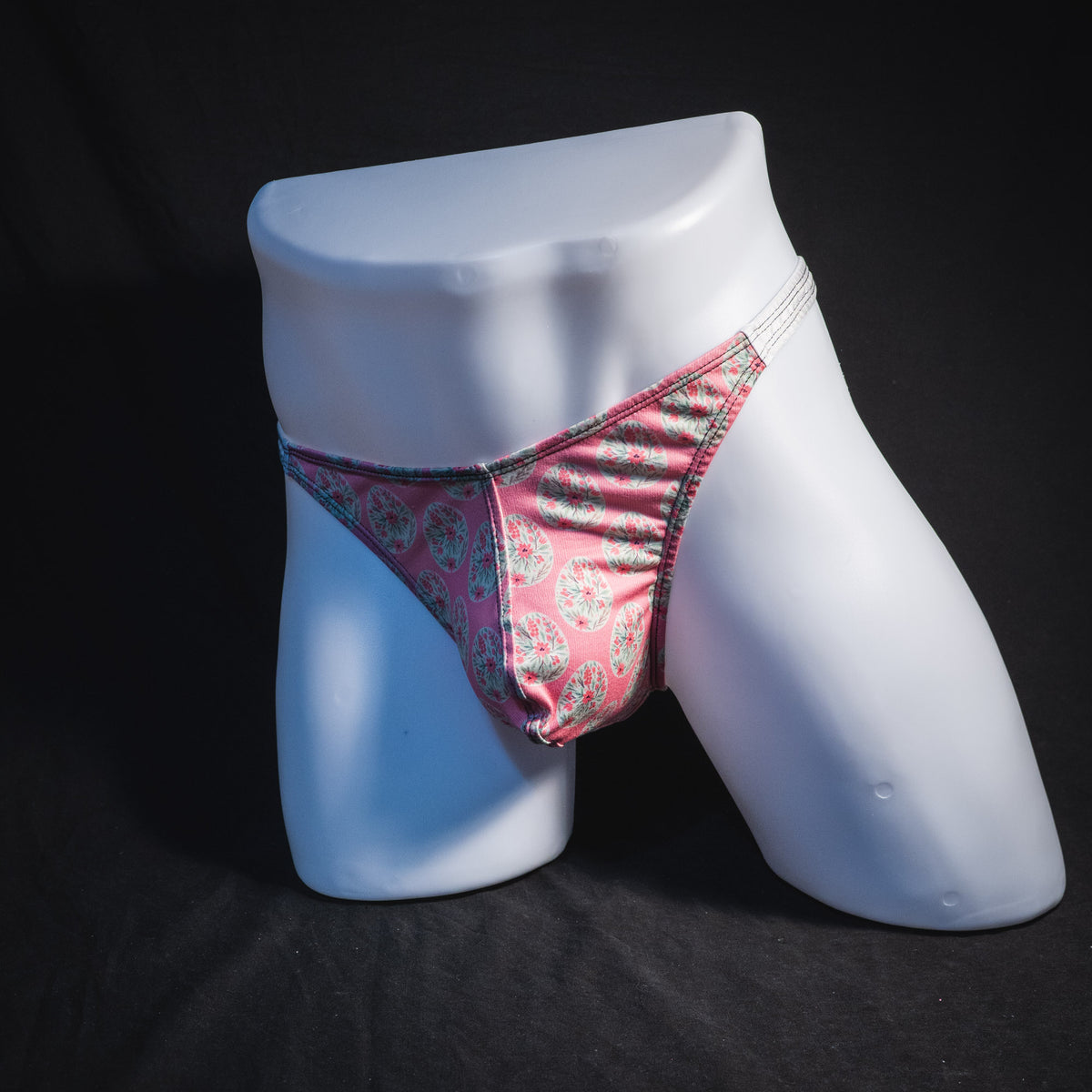 Men's pink painted easter eggs thong underwear, classic cut, full angled front view.