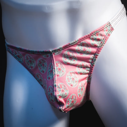 Men's pink painted easter eggs thong underwear, classic cut, angled front view.