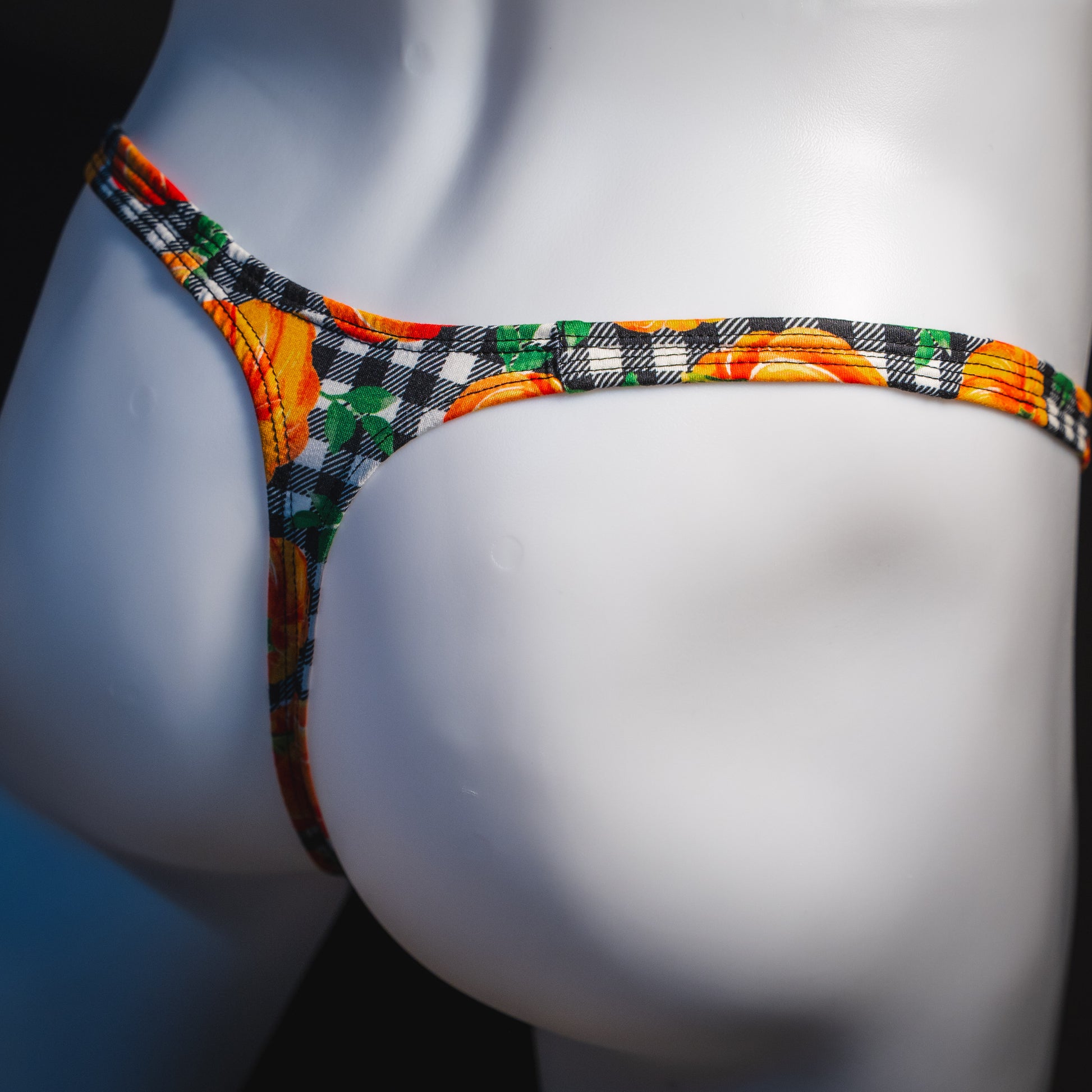 Men's pumpkin and plaid thong underwear, classic cut, angled rear view.