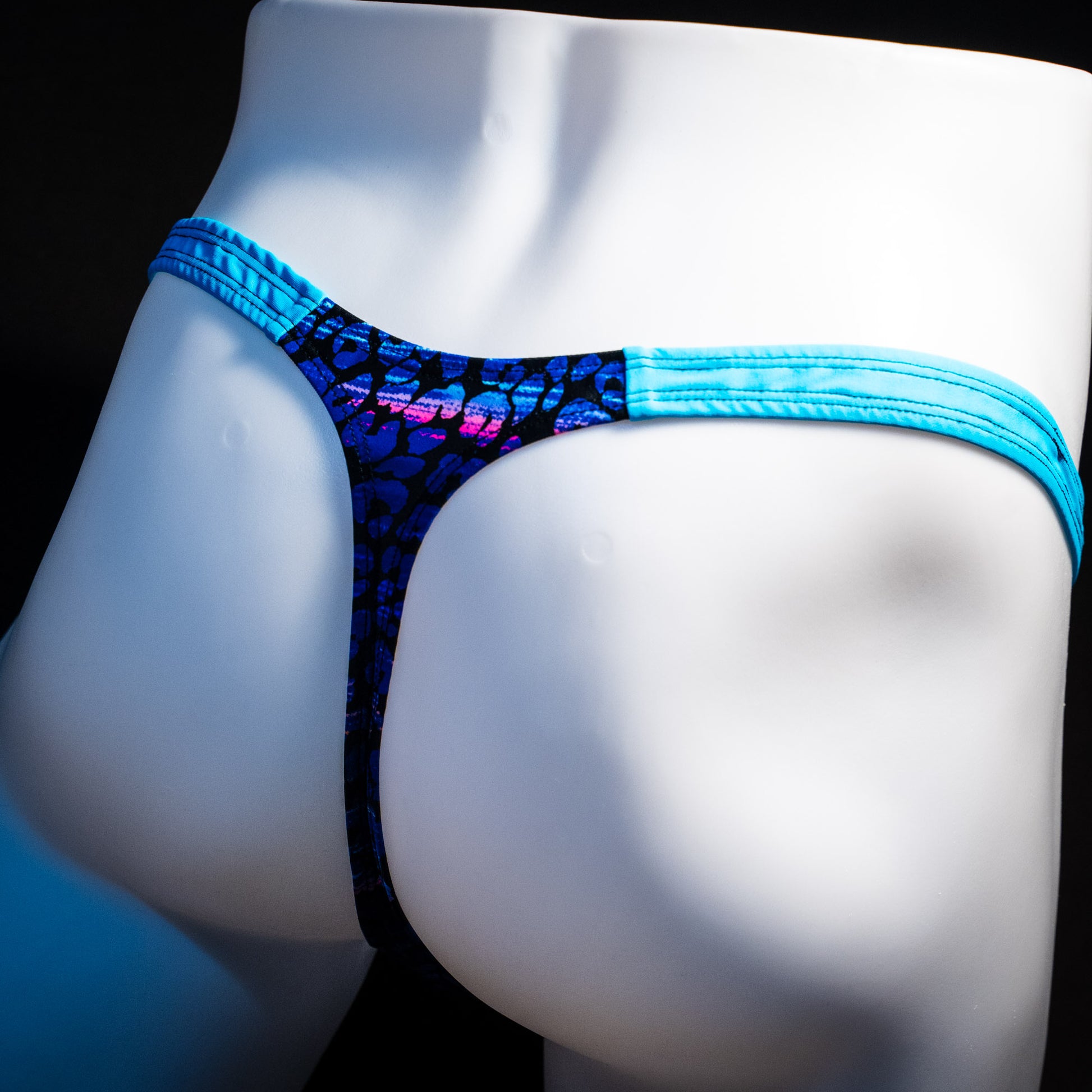 Men's purple and blue cheetah thong underwear, classic cut, rear angled view.