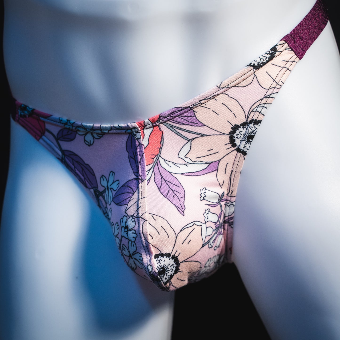 Men's purple floral thong underwear, classic cut, angled front view.