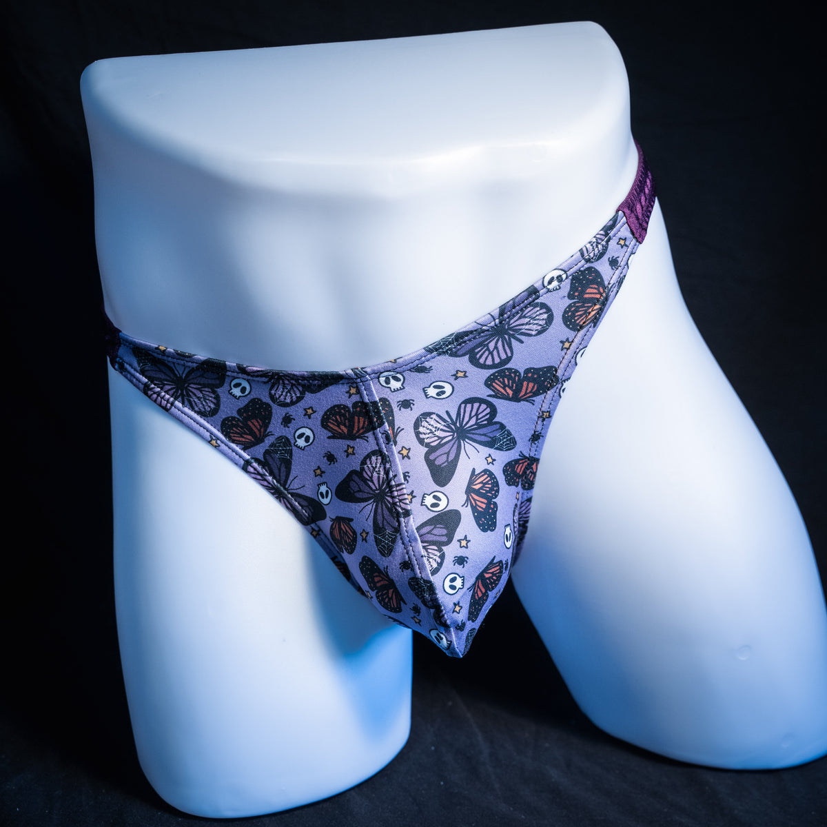Men's purple skulls and butterflies thong underwear, classic cut, front view.