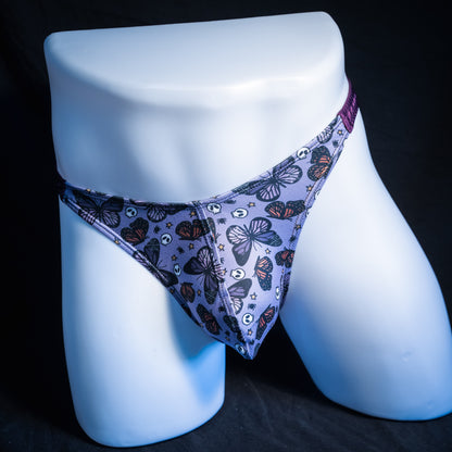 Men's purple skulls and butterflies thong underwear, classic cut, front view.