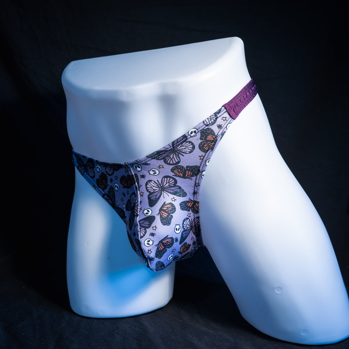Men's purple skulls and butterflies thong underwear, classic cut, front view.