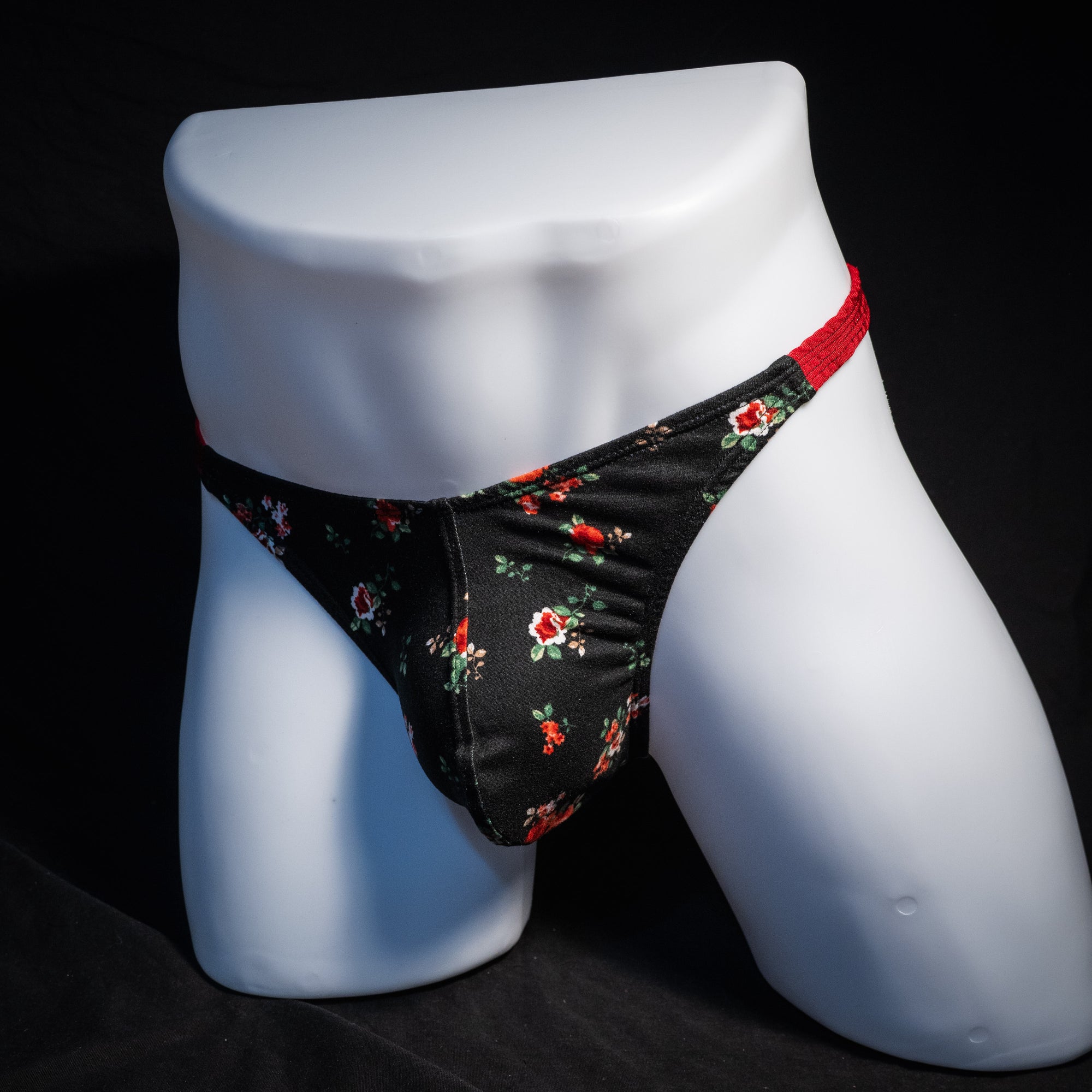 Men's red and black floral thong underwear, classic cut, front view.