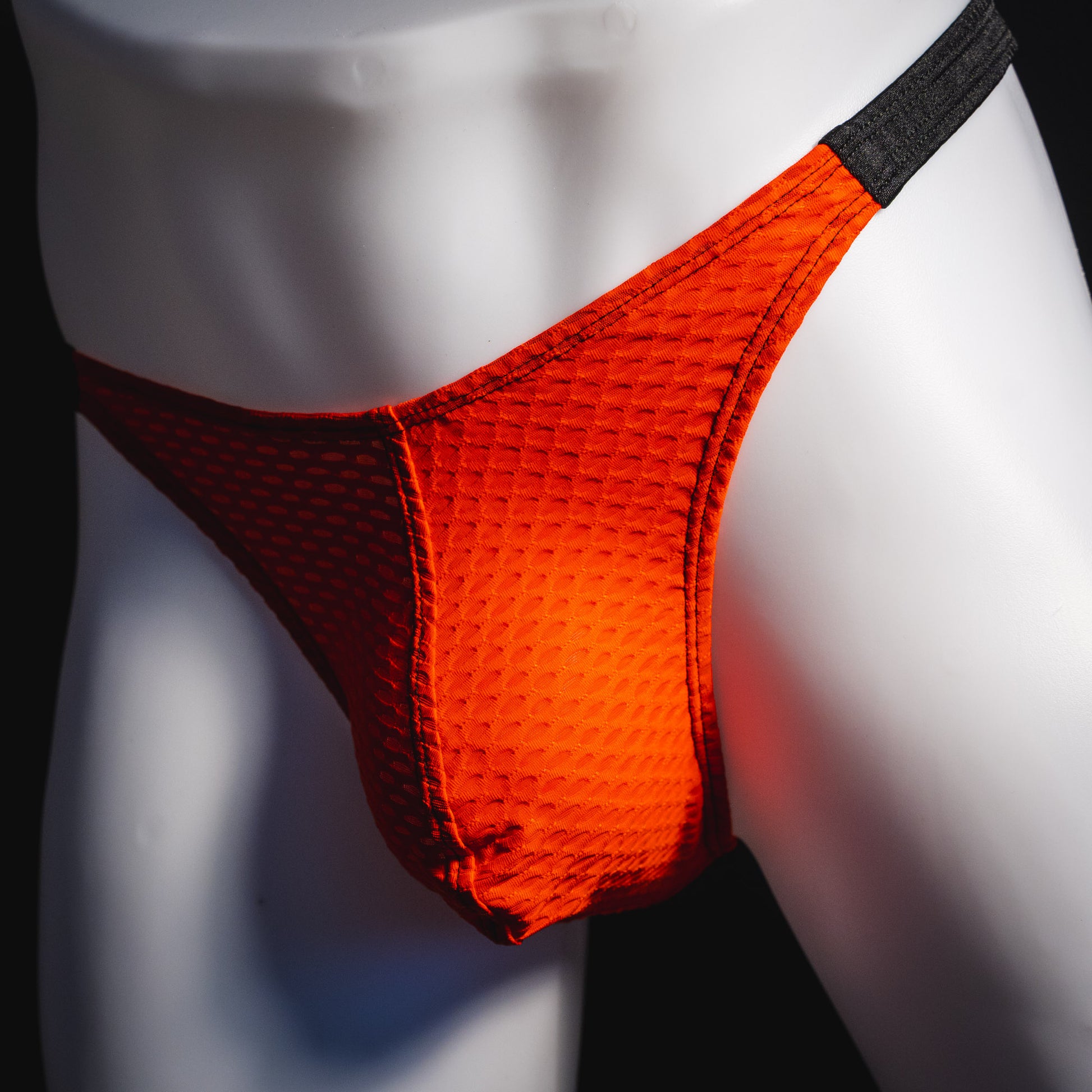 Men's red and black athletic mesh thong underwear, classic cut, angled front view.