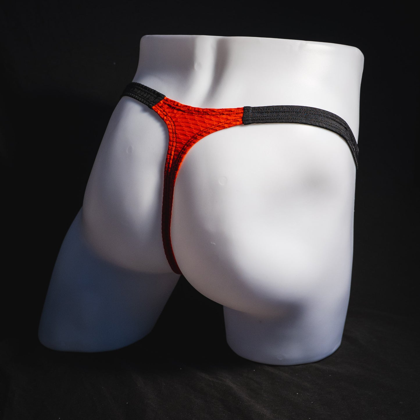 Men's red and black athletic mesh thong underwear, classic cut, full angled rear view.