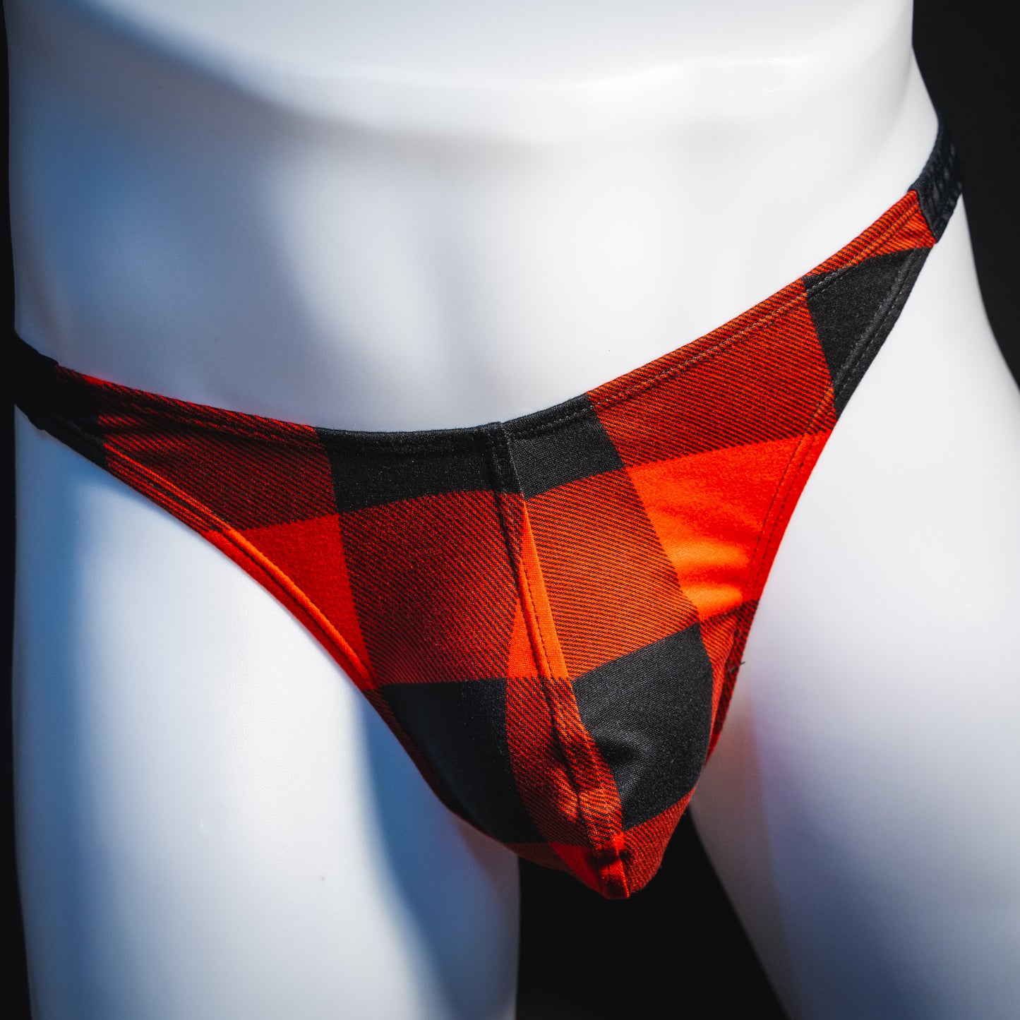 Men's red plaid with black straps thong underwear, classic cut, front view.