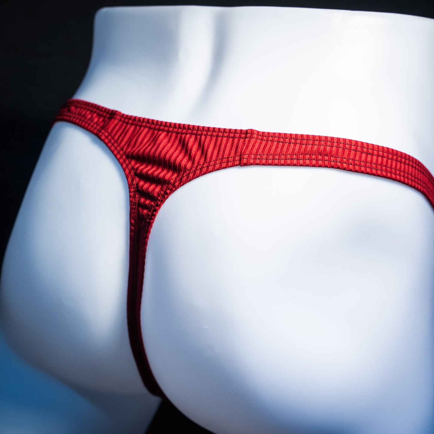 Men's ribbed red thong underwear, slim cut, rear view.