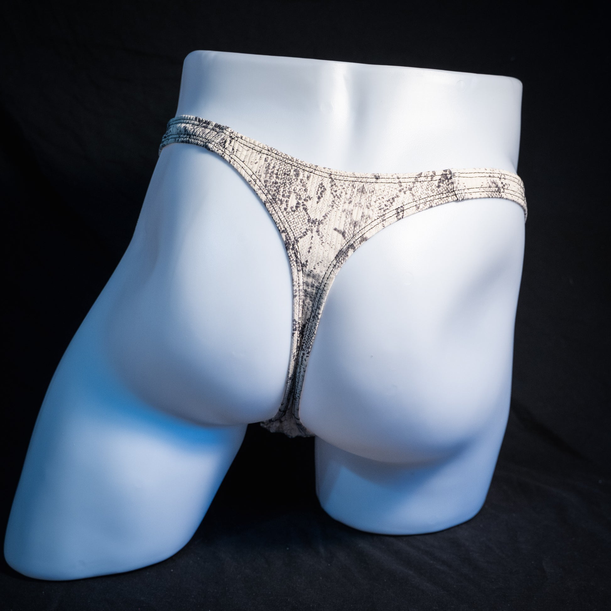 Men's beige snakeskin thong underwear, ribbed fabric, slim cut, rear view.